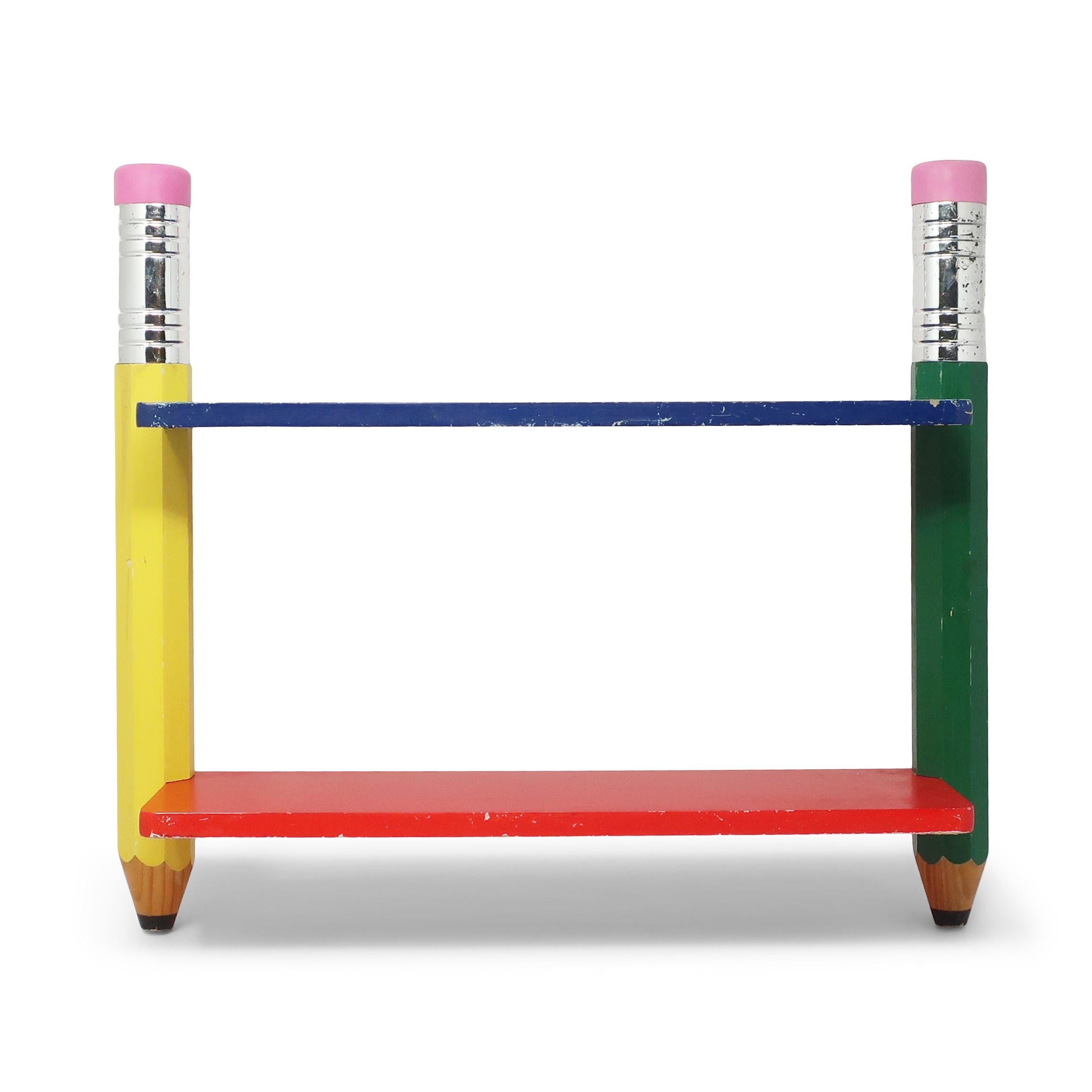 A great piece from Pierre Sala's postmodern pencil-themed children's furniture from the 1980s for Pierre Sala Furniture.  Design is composed of two shelves, one blue and red, supported by two pencils, one yellow and one green.  Includes rings on