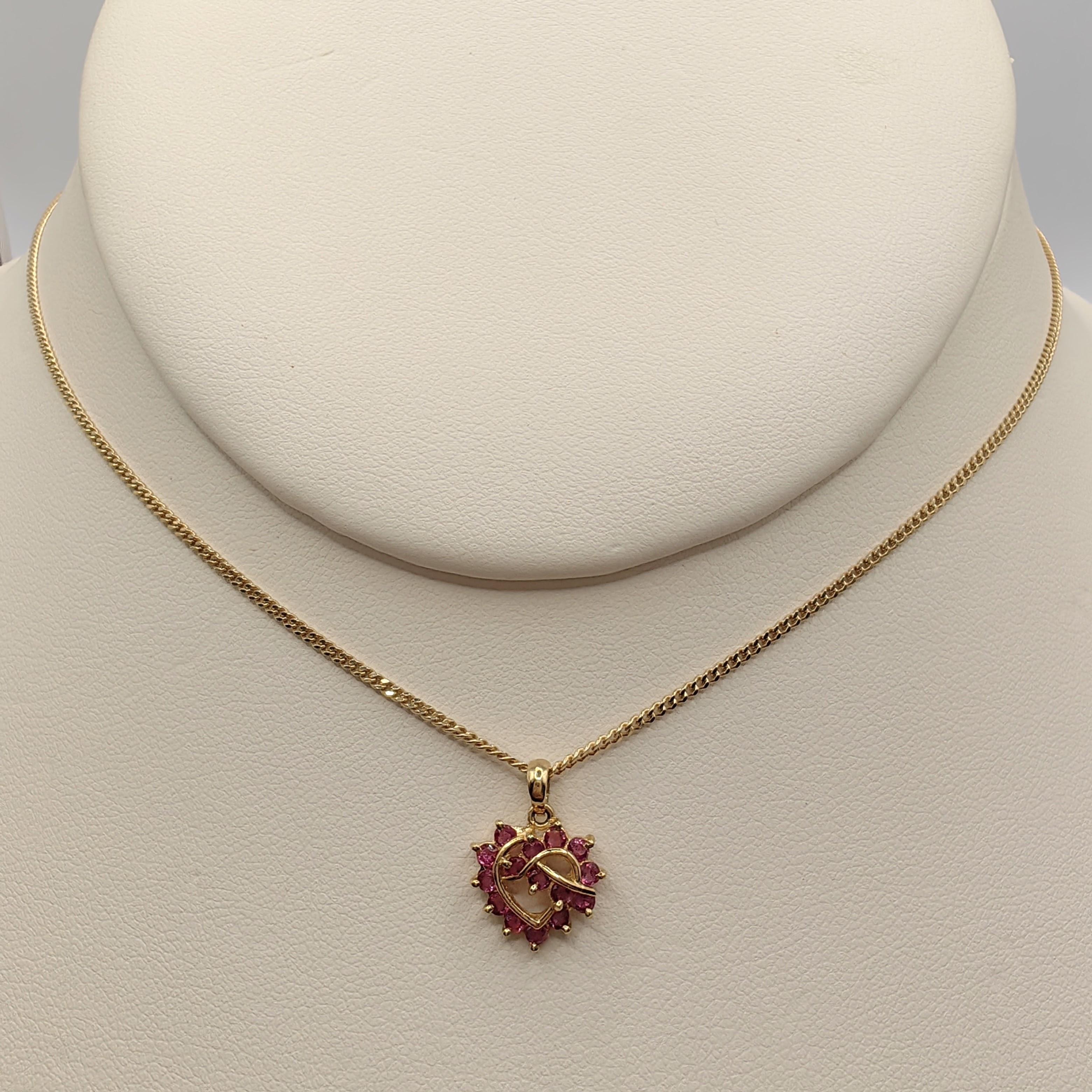 Entrez dans le monde enchanteur des années 80 avec notre pendentif Vintage Ruby Heart Necklace en or jaune 14 carats. Un motif en forme de cœur gracieusement torsadé vole la vedette, orné de 15 rubis de taille ronde totalisant environ 0,30 carat.