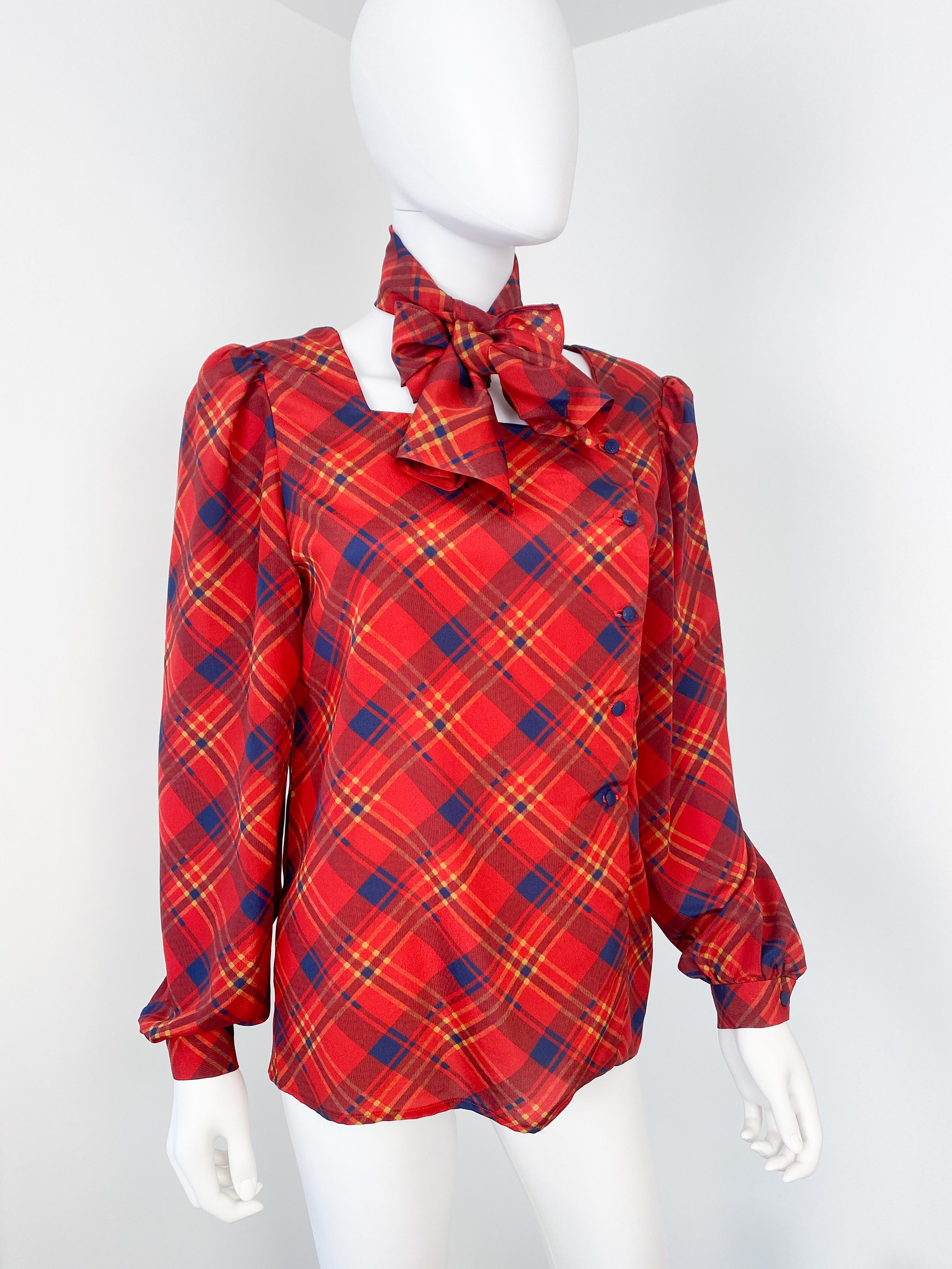 Wonderful vintage 1980s silky polyester blouse with additional bow scarf to create versatile looks. Red color fabric with tartan pattern and blue and yellow contrast. The unusual square collar shape has the buttons closing asymmetric and located on