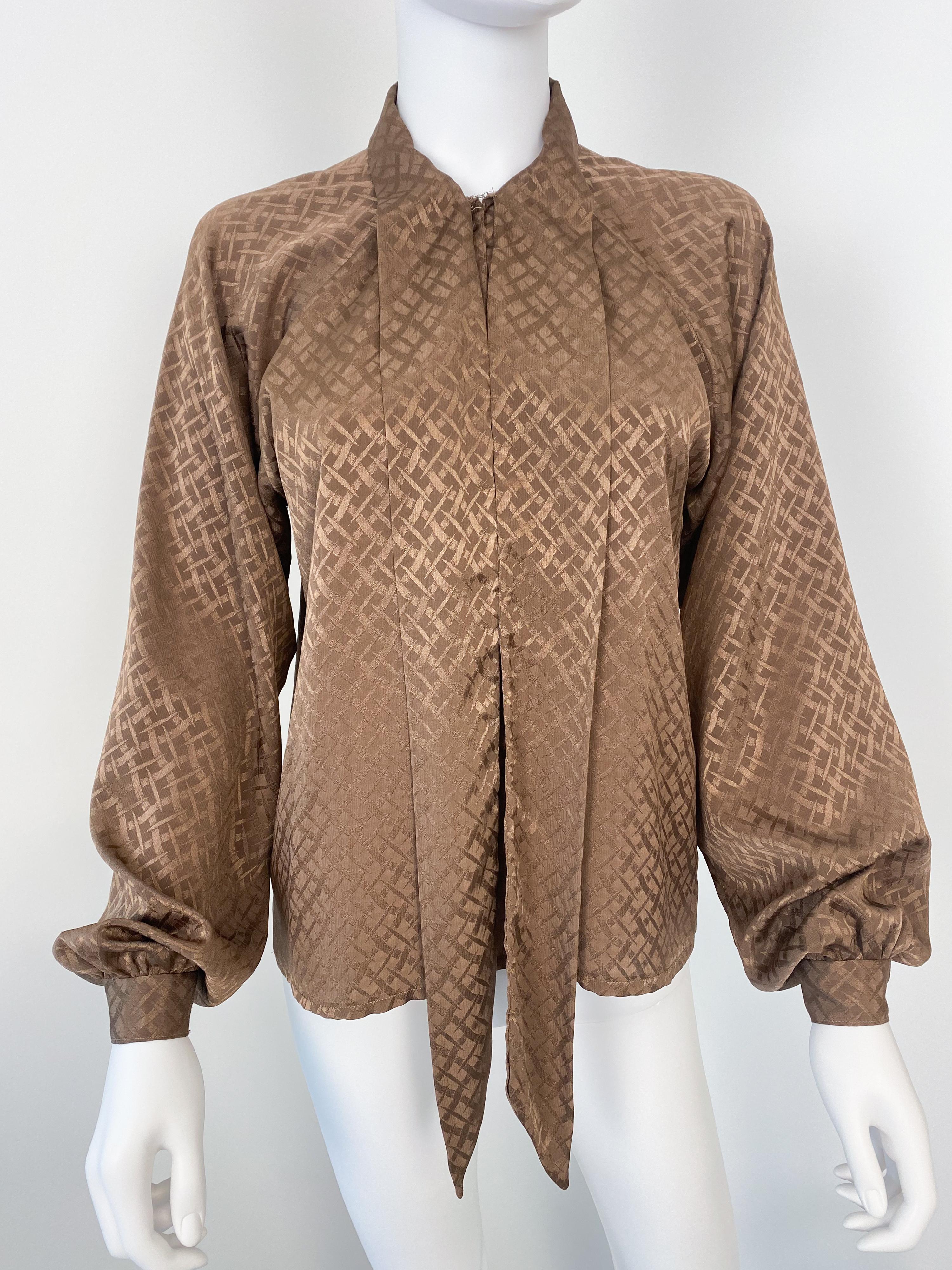 Wonderful vintage 1980s silky polyester pussy bow blouse in a peasant-style silhouette with attached scarf-bow. Cocoa brown color fabric with tone-on-tone geometric pattern. The pullover construction has a partially open front with a metal hook at