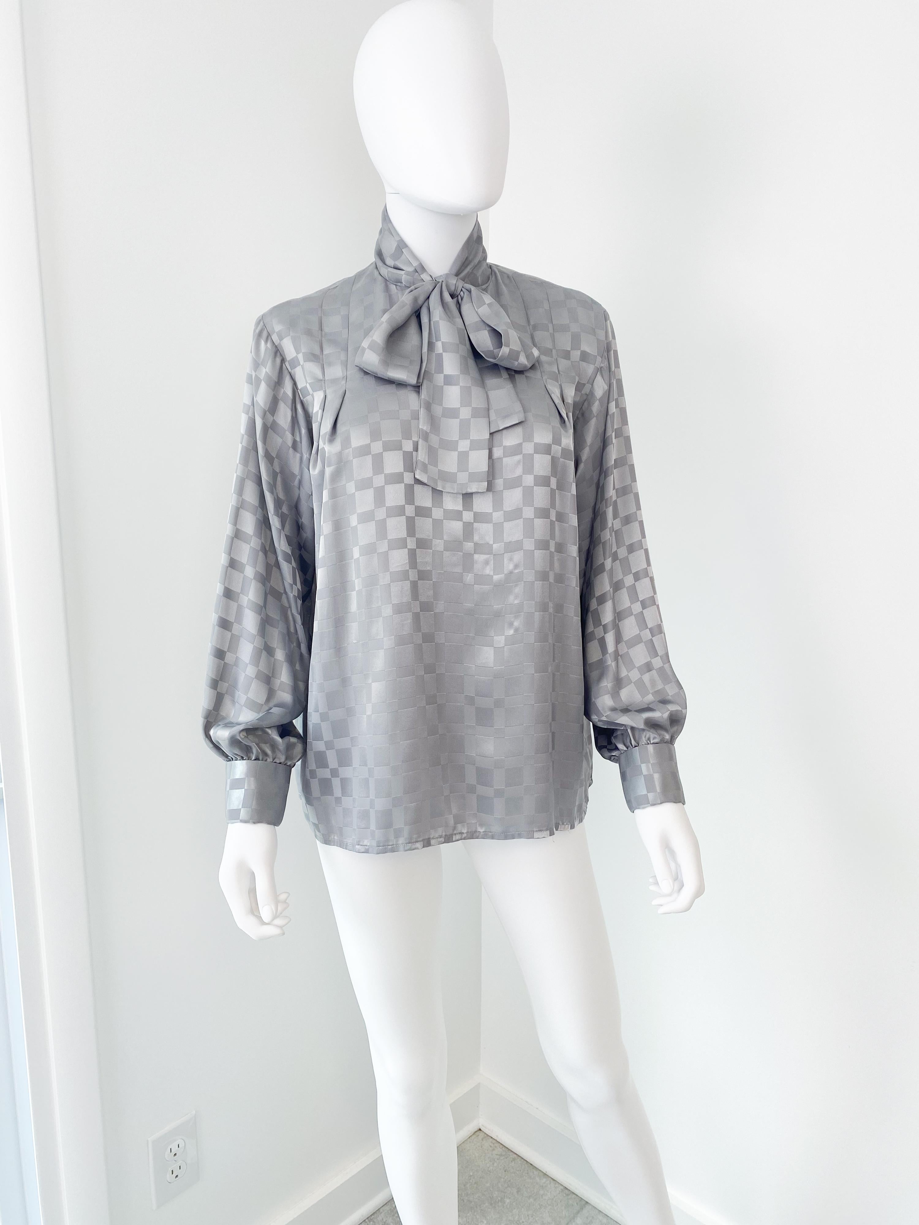 Deliziosa camicetta vintage anni '80 in poliestere con fiocco di figa in stile contadino e foulard annesso. Tessuto grigio topo con motivo geometrico tono su tono. La struttura del pullover è parzialmente aperta sul davanti e presenta un gancio