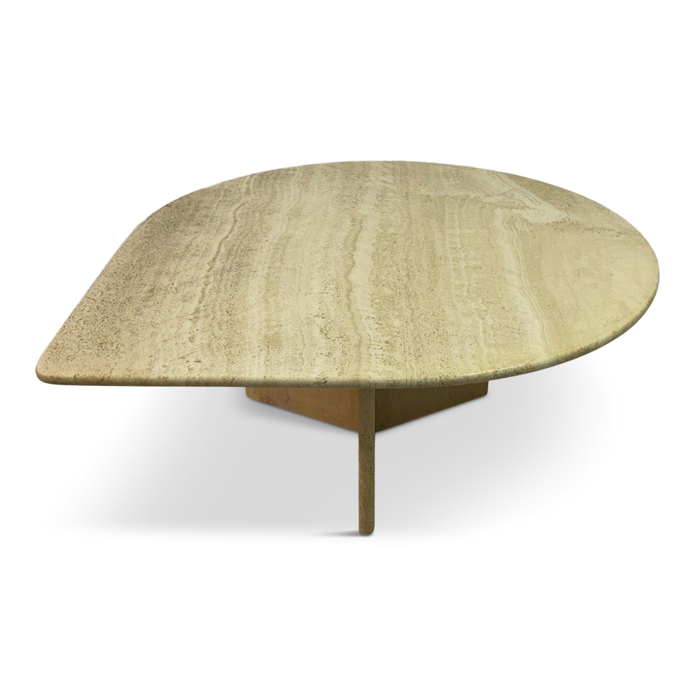 Table en travertin en forme de goutte d'eau datant des années 1980. Le plateau de la table présente une surface lisse et polie qui met en valeur les tons naturels de beige crème et les veines subtiles typiques de la pierre de travertin. Sa forme
