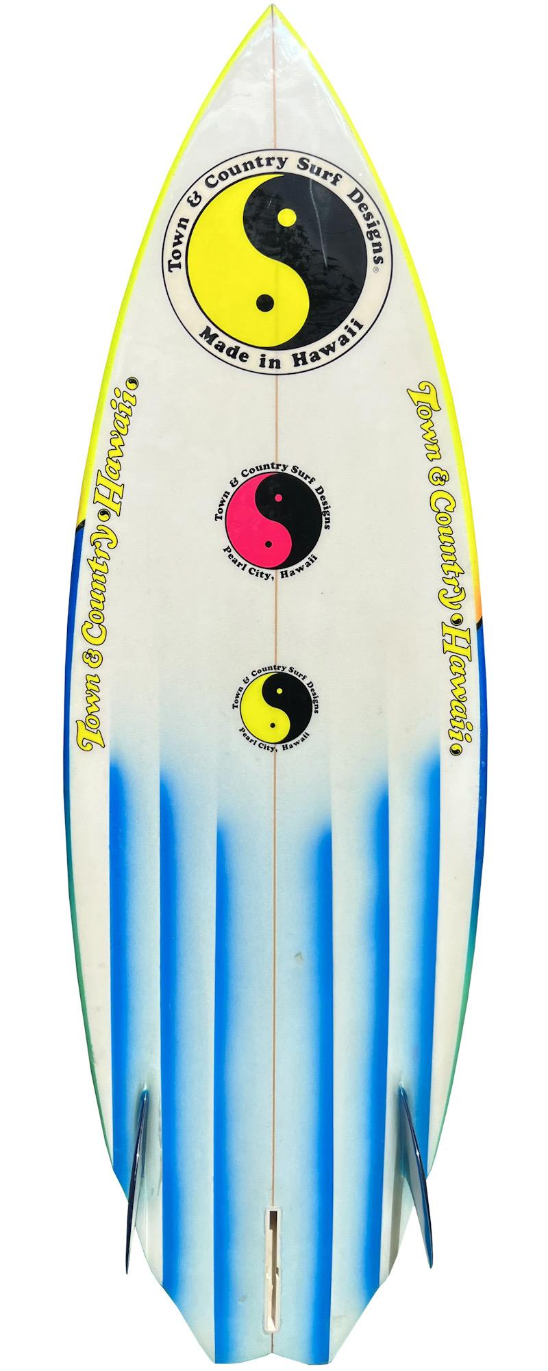 1983 Town and Country (T&C) shortboard made by Dave Wallace. Features a vibrant airbrush design indicative of the 1980s. Double wing swallow-tail shape design with distinct channel bottom. 2+1 fin setup. An incredible example of a colorful 1980s