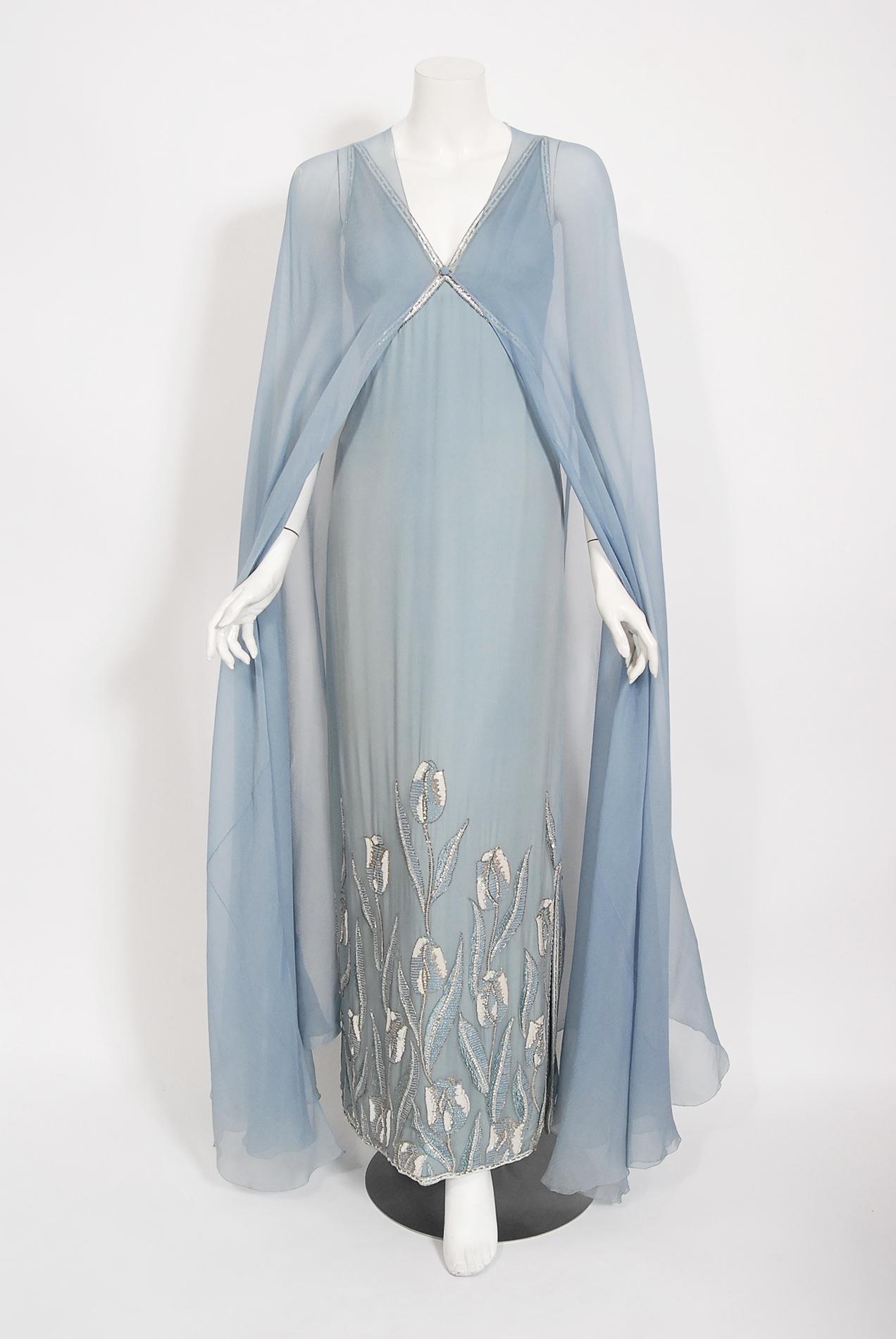 Chanel ist bekannt als eines der luxuriösesten und dekadentesten Modehäuser der Welt. Dieses atemberaubende:: puderblaue Kleid mit passendem:: bodenlangem Umhang aus der Haute-Couture-Kollektion Frühjahr/Sommer 1981 ist ein perfektes Beispiel