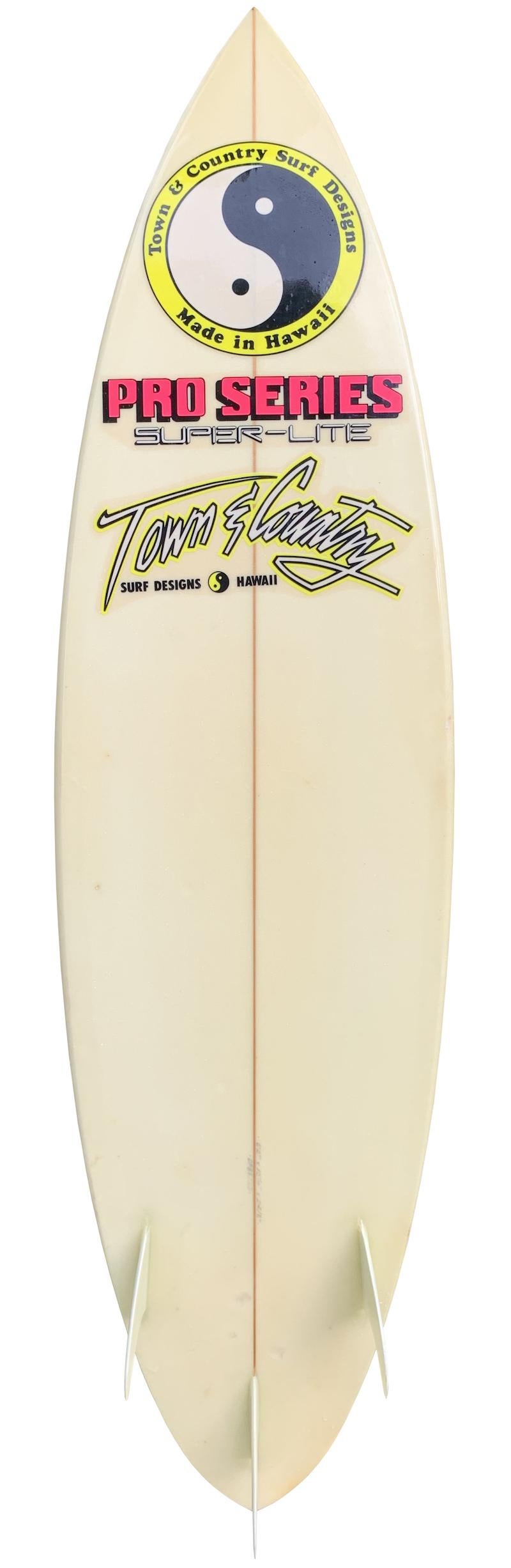 1988 Town & Country thruster (tri-fin) shortboard surfboard shaped by Dennis Pang. Features a vintage 1980s airbrush design with glassed on fins. A remarkable example of a late 1980s vintage T&C surfboard made in Hawaii. This vintage surfboard