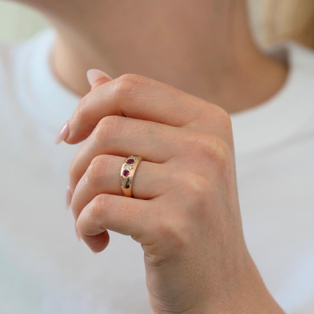 A bold yet classic piece, this vintage ruby and diamond gypsy ring was made in 1990 and crafted in warm 9ct rose gold. The ring features a trio of vivid round-cut rubies, each set in diamond-shaped settings with a lovely flush finish. Between them