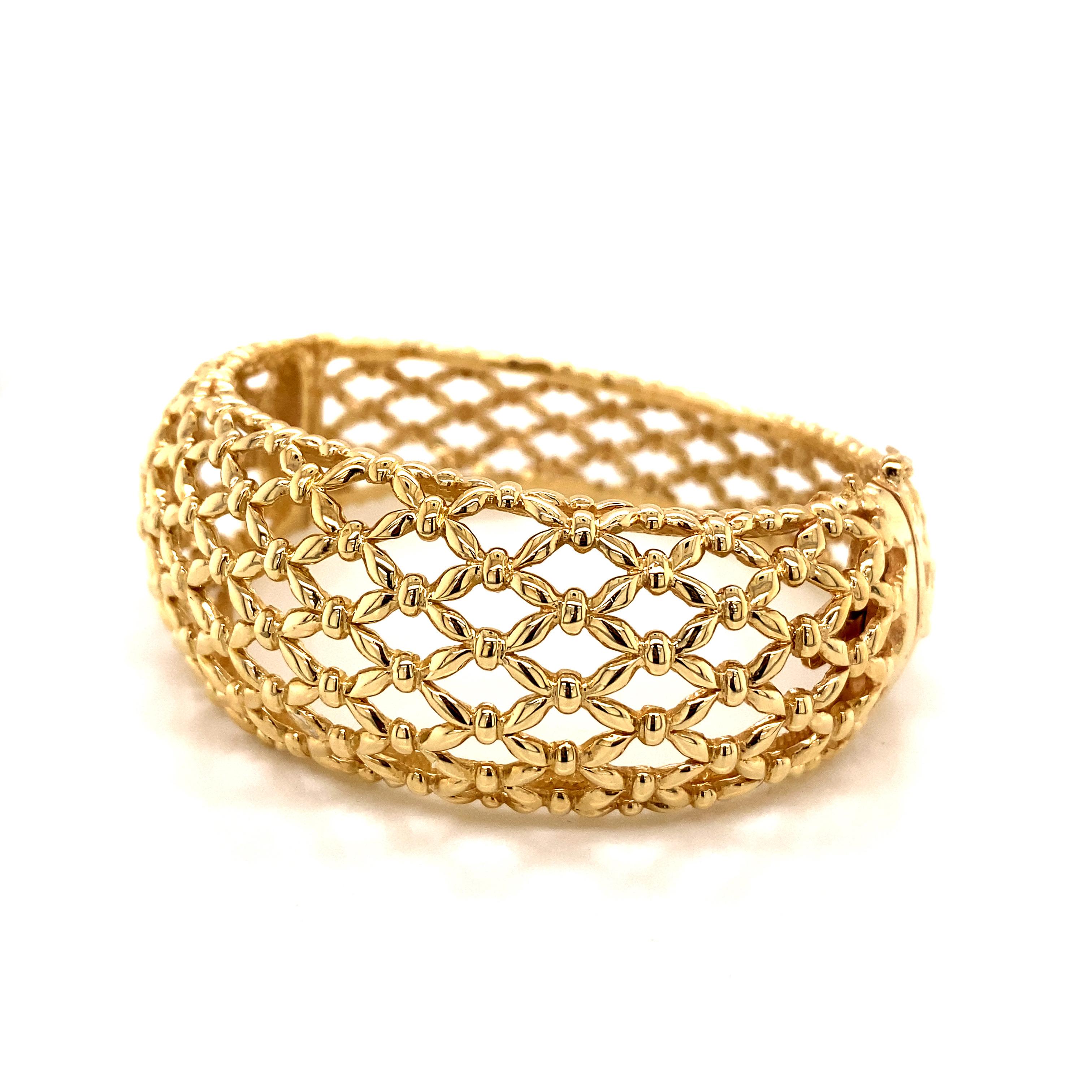 A true masterpiece of 1990s craftsmanship, this showstopping bangle bracelet showcases the artistry of intricate basket weave metalwork. Rendered in lush 14k yellow gold, the bracelet features a unique tapering design that creates a sculptural,
