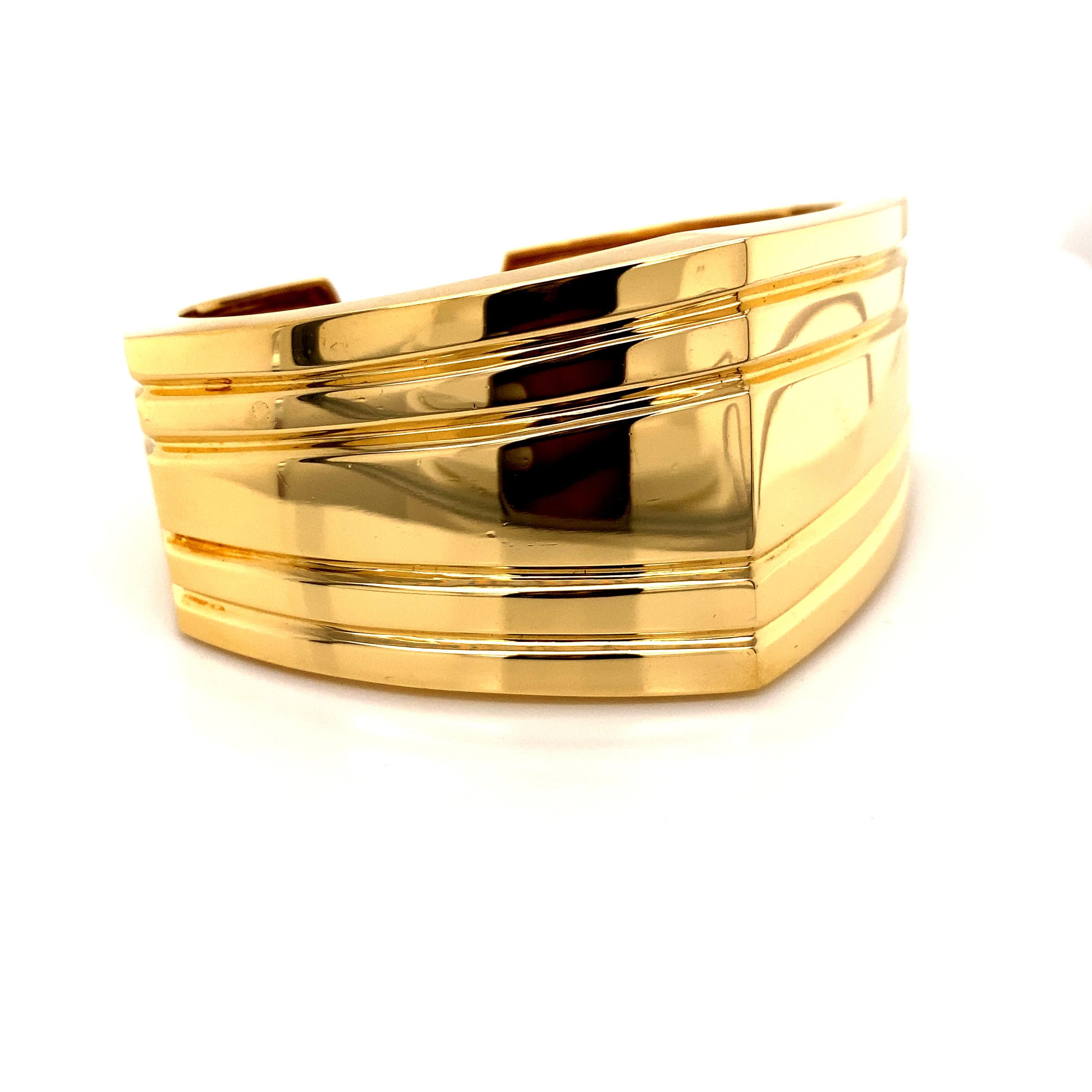 A true showcase of 1990s design aesthetics, this striking 18k yellow gold cuff bangle makes a powerful geometric statement. Crafted from luxurious 18k gold, the bangle features a bold, angular shape with an eye-catching wide silhouette. 

At its