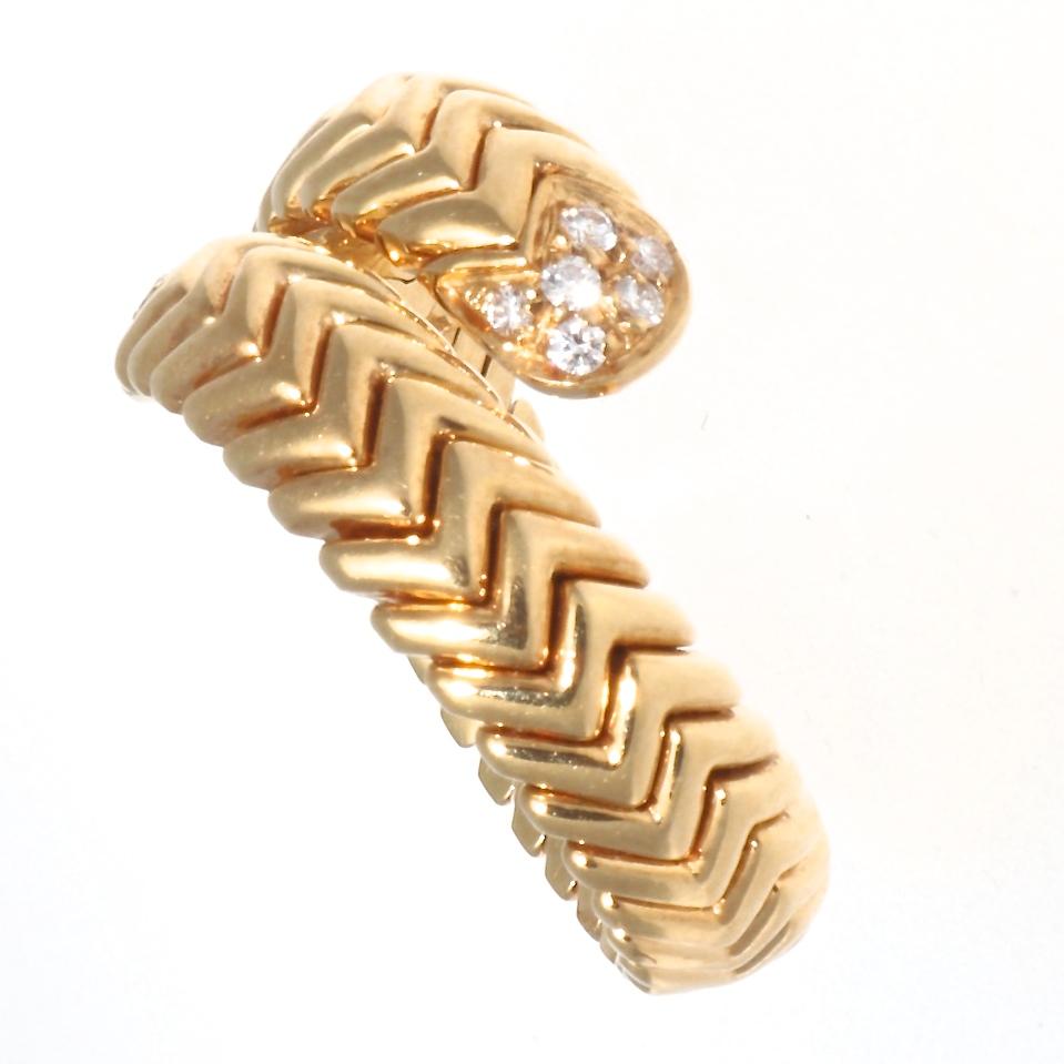 The classic Bulgari style in a fabulous bypass ring with diamonds and the iconic sectioned gold design we've come to recognize as uniquely Bvlgari. This 18k yellow gold spiga ring contains 12 round brilliant diamonds that weigh approximately 0.25