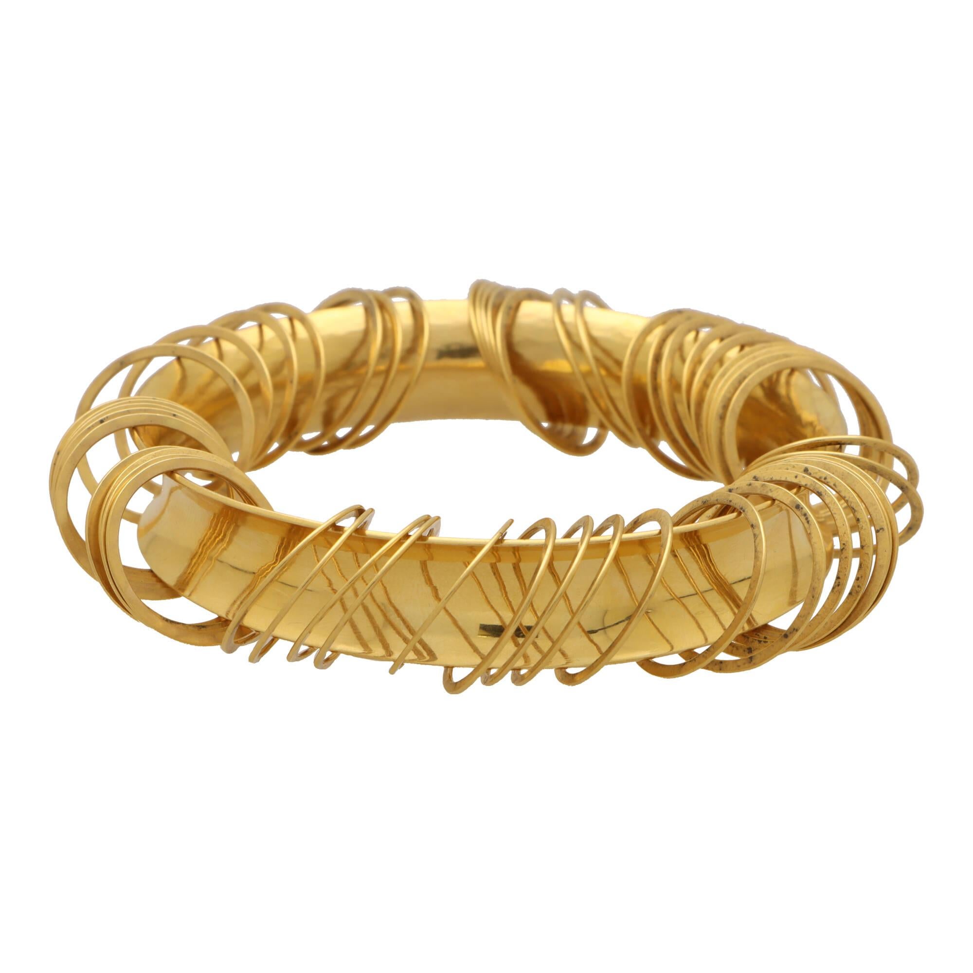 An extremely unique vintage 1990’s concave bangle in 22k yellow gold.

The bangle is composed in a solid 22k yellow gold concave design with a subtle hammered effect on the inside. Interestingly, attached and hanging from the bangle are 50 circular