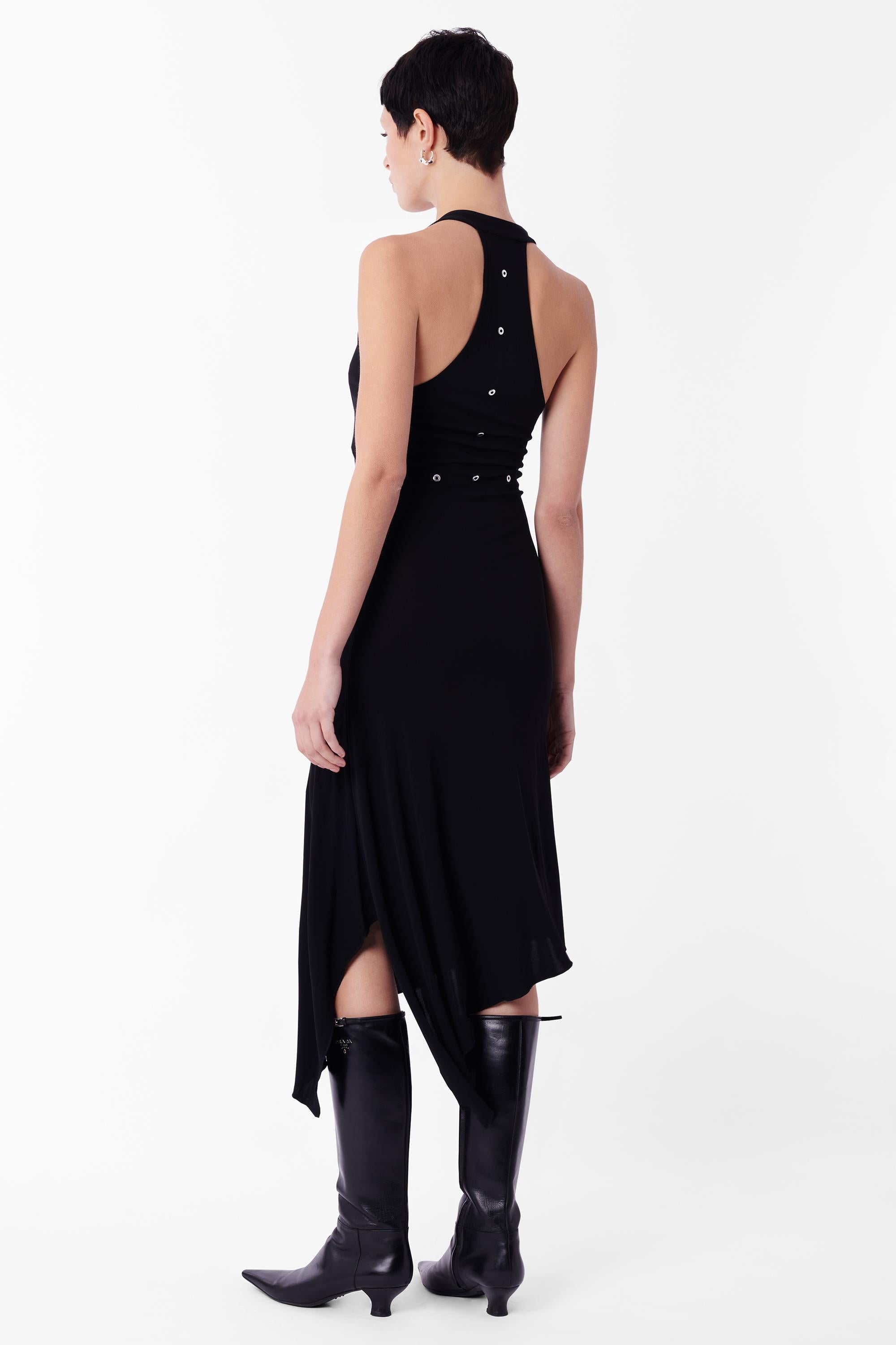 Abito asimmetrico nero Mugler vintage anni '90. Presenta un taglio profondo con scollatura racerback, una silhouette con collo halter, una fodera con occhielli argentati sotto il seno e un orlo asimmetrico. In eccellenti condizioni vintage.