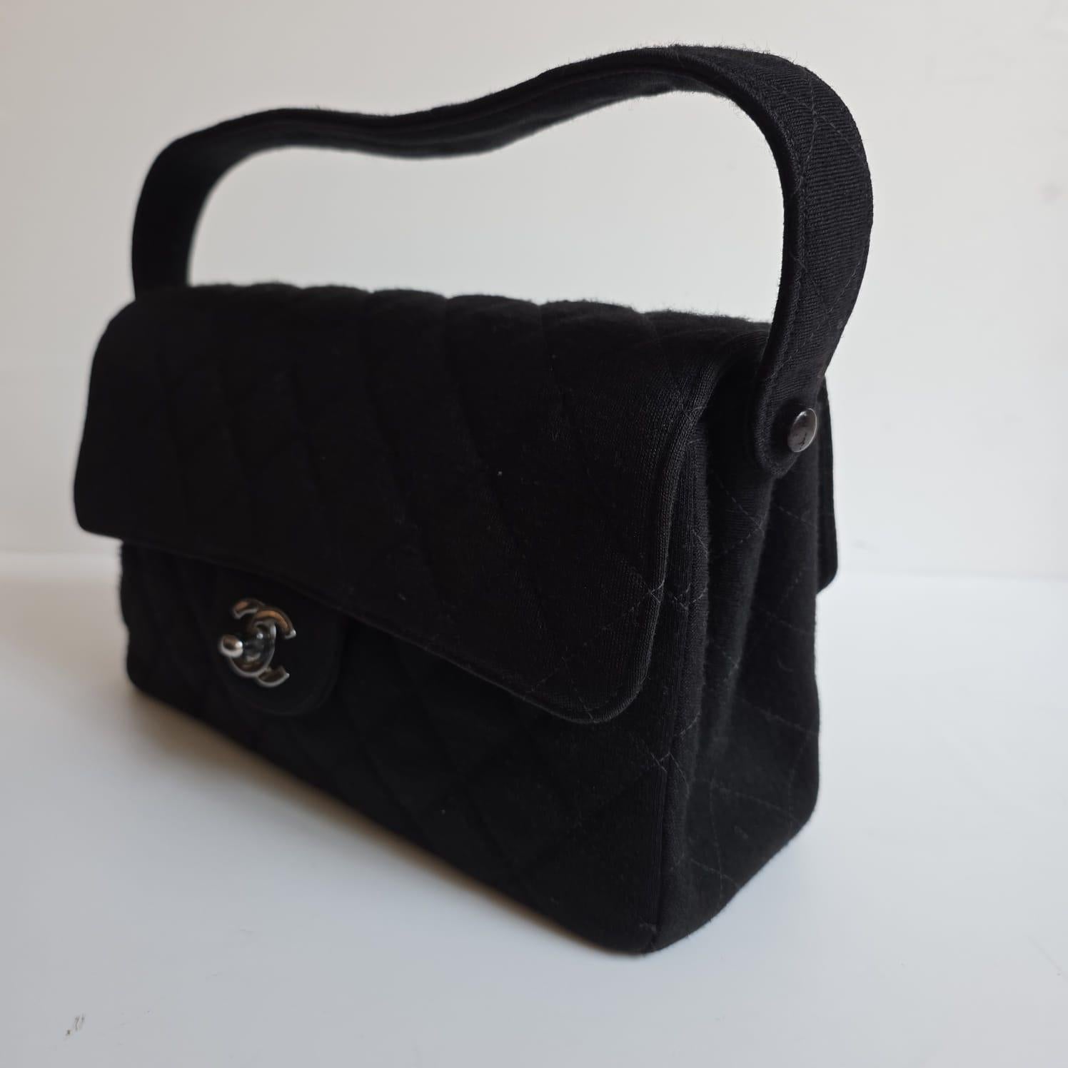 Vintage Chanel, poignée biface moyenne en jersey noir avec quincaillerie argentée. Il n'y a pas de traction importante sur le tissu. Petites éraflures sur les détails en cuir. Série n°4. Livré avec holo, carte et livret uniquement.