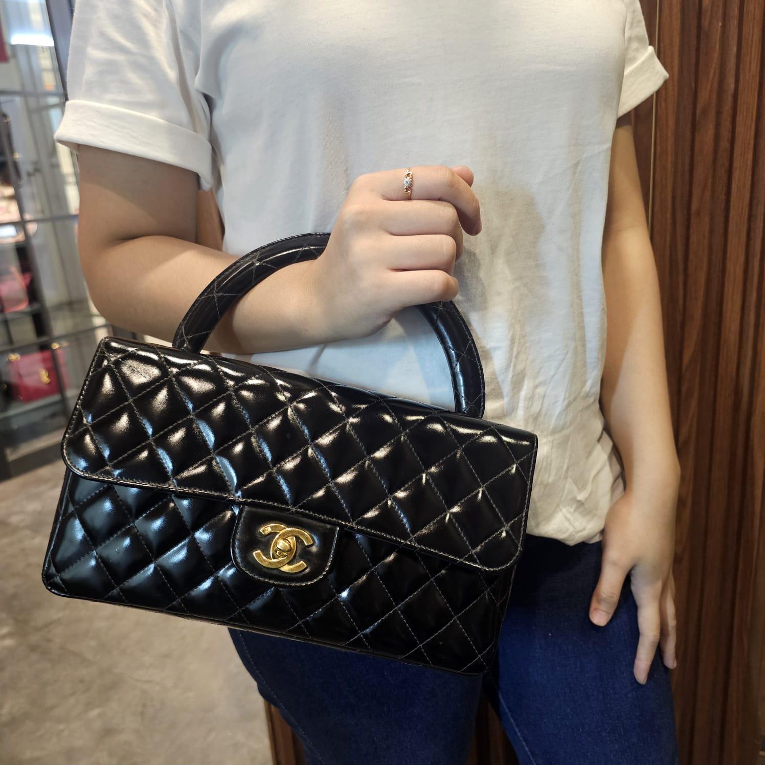 One of the iconic Chanel vintage top handle style bag in black patent with gold hardware. Overall the patent leather is still in good condition with slight cloudiness to it. Minor rubbing on the corners and lining. Visible spot marks on the leather