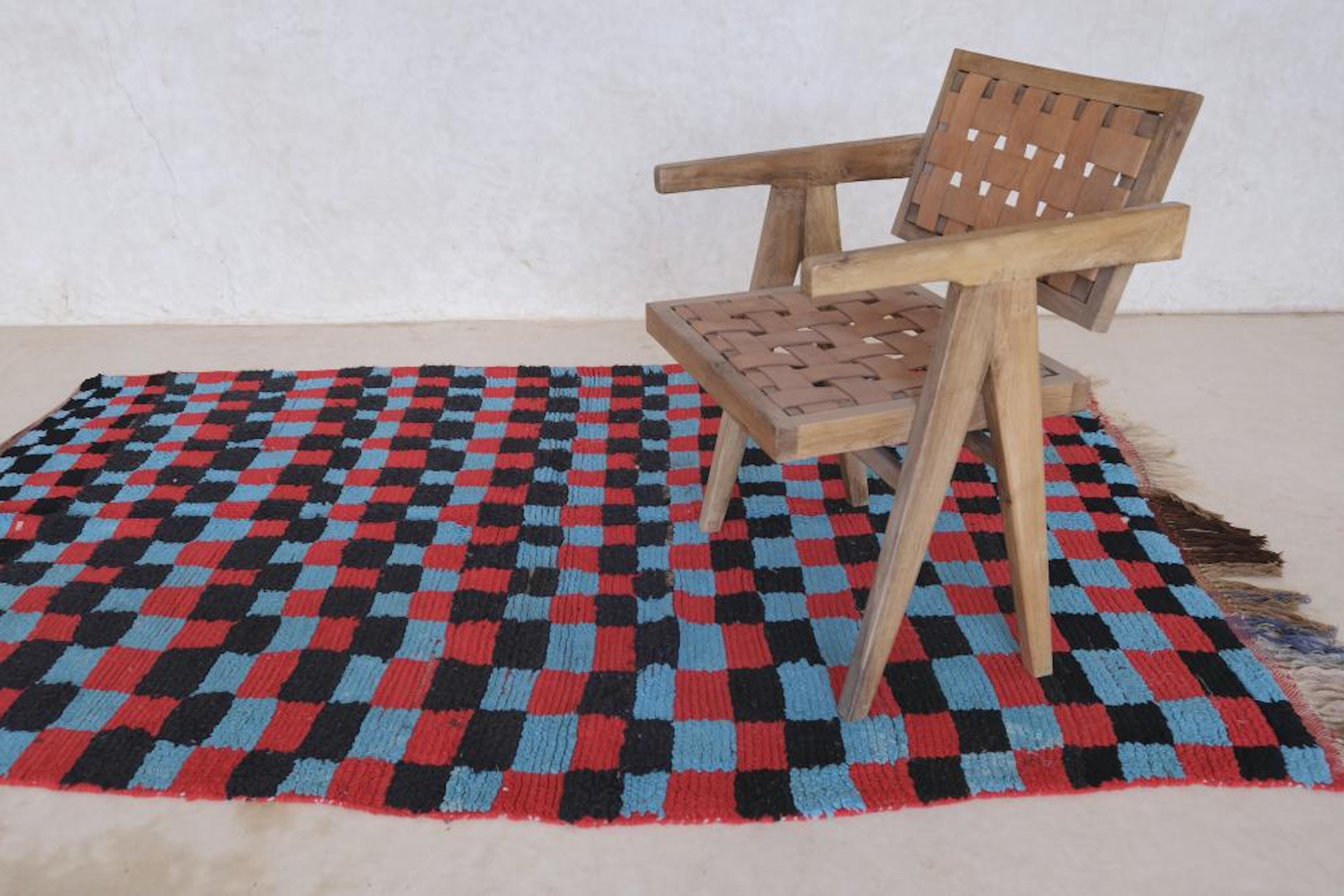 Se trata de una alfombra marroquí vintage a cuadros muy chula de la tribu Boujaad. La atrevida lana negra, azul y roja hace que destaque esta pieza bohemia a cuadros. Fue tejida a mano en Marruecos en algún momento de la década de 1990, y ahora