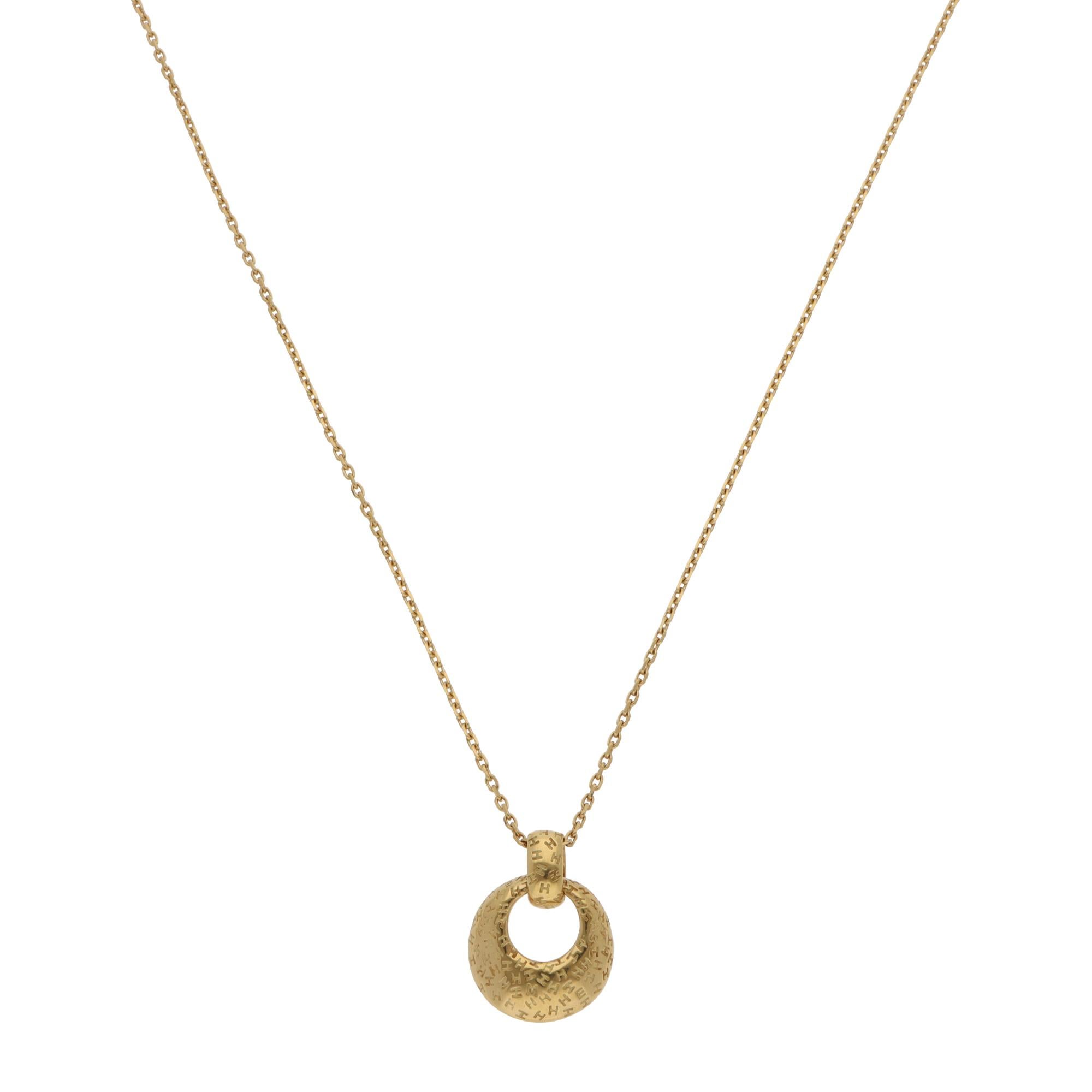 A gorgeous vintage Hermès open circle pendant necklace set in 18k yellow gold, circa 1990's.

The pendant depicts a polished yellow gold open circle motif stamped with the letters H, E, M and S in a randomised pattern. It connects to a yellow gold