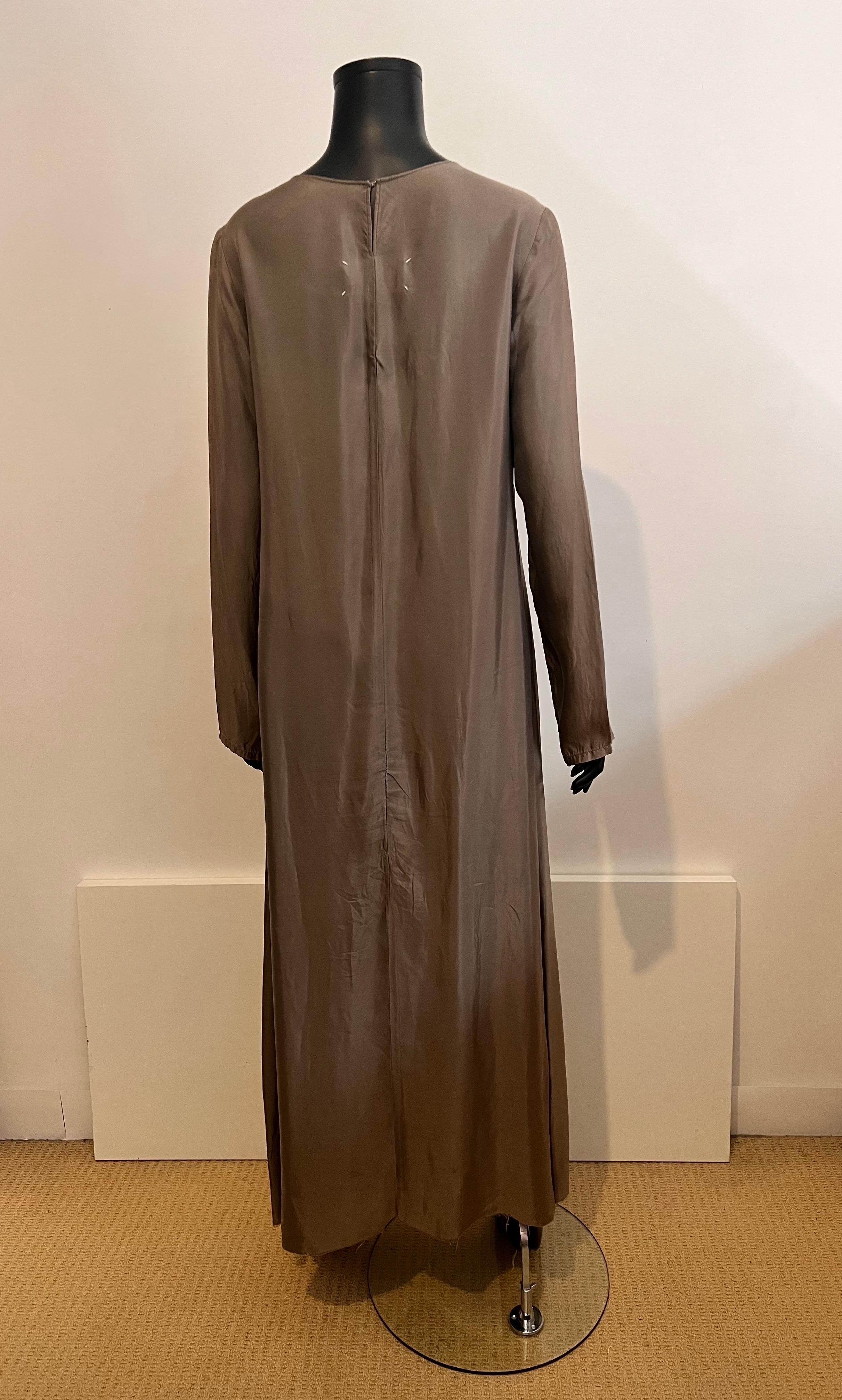 This piece epitomises the deconstructed era of the Margiela house in the 1990’s.

A maxi length, A line shaped dress in a signature colour for the house (taupe/olive) with grey felt patches worked /added randomly over the garment creates a piece