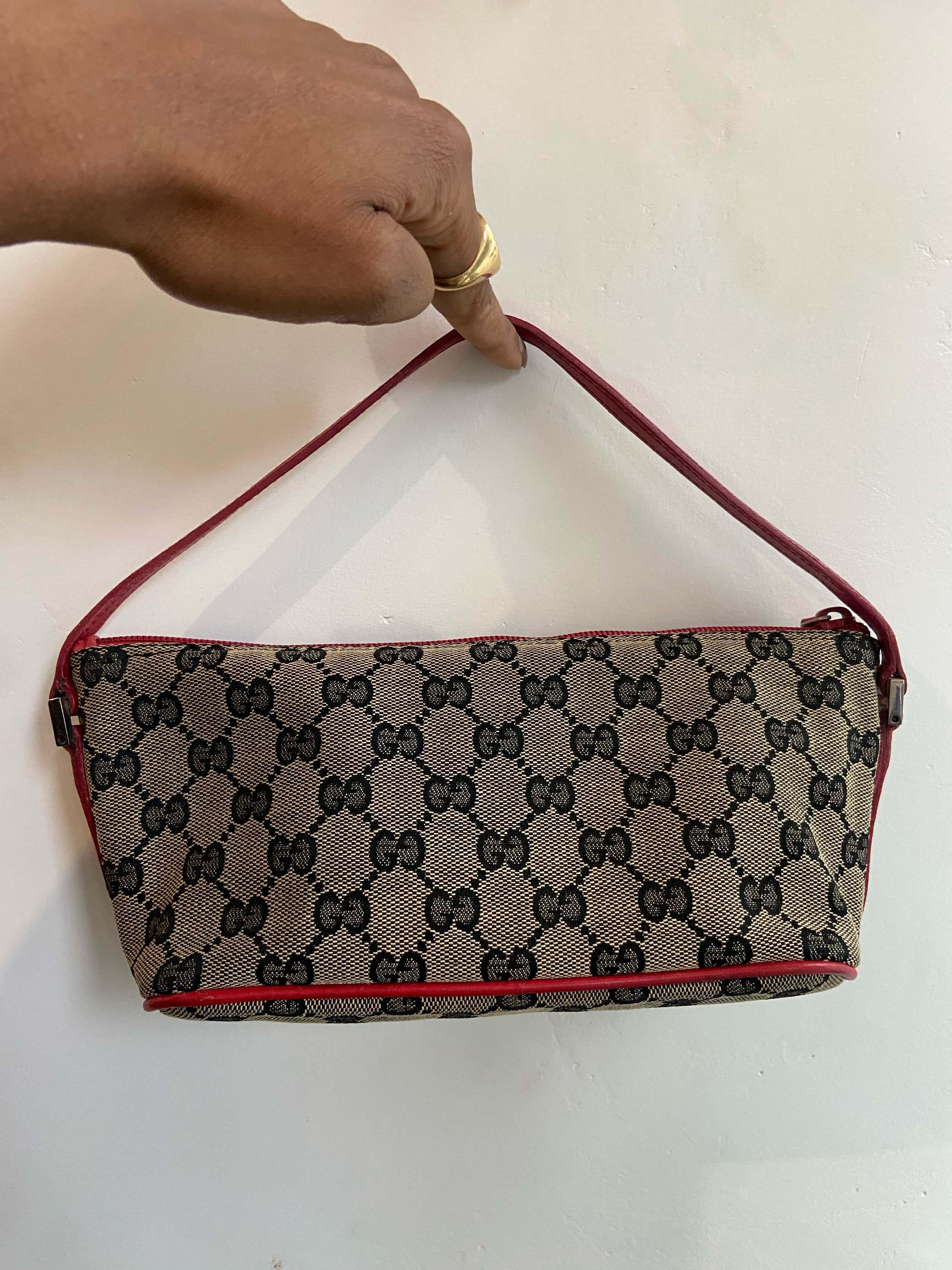Gucci Circa 1990’s “GG” monogram boat canvas pochette bag. Features a rare red leather trim and strap and a silver Gucci front logo tone hardware. Fastens with a top zipper. 

Brand: Gucci
Color: Brown/ Red
Year/ Season : Circa 1990’s
Boat