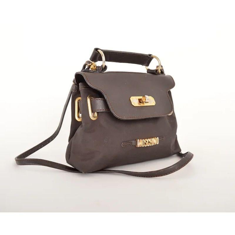 A Chic and Fun Vintage 1990's Moschino brown nylon miniature 'Kelly' bag with gold tone metal hardware and leather features. 

Features:
Detacheable shoulder strap
Belt loop option
Top handle
MOSCHINO Gold Tone Metal lettering

Made In