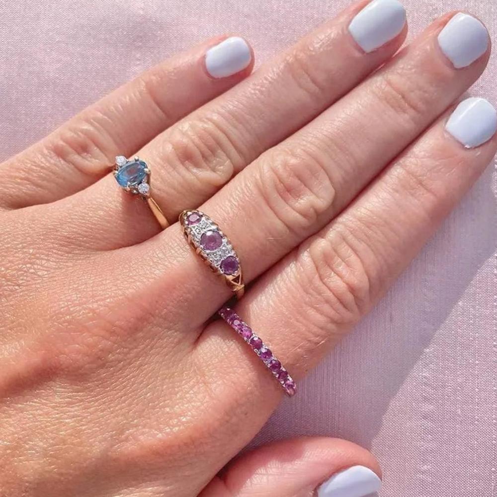 Unser wunderschöner Saphirring aus 9-karätigem Gold besteht aus drei großen rosa Saphiren, die mit vier Diamanten besetzt sind. Der Ring ist mit einer Reihe von Punzen versehen, die darauf hinweisen, dass das Stück 1992 in London, England,