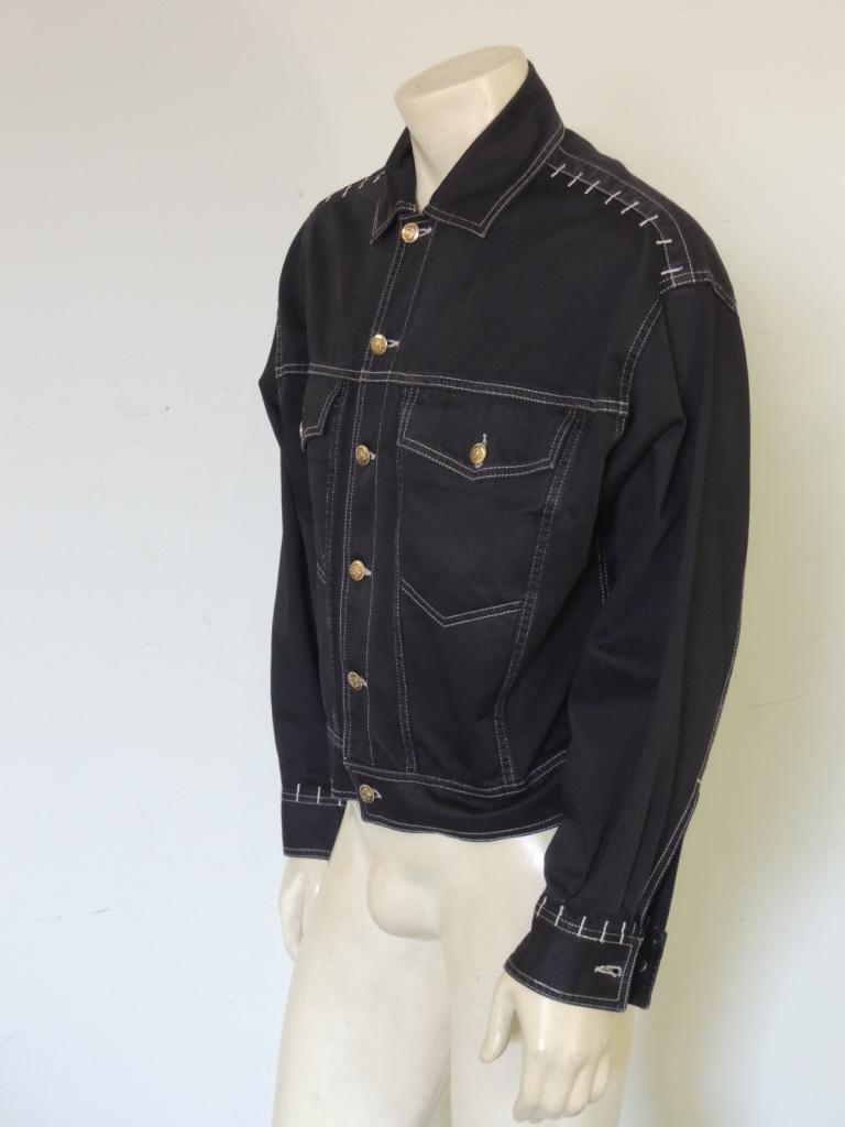 This is a vintage black Versace Jeans Couture denim jean jacket with logo Medusa buttons, estimating 1990s era. 

The fabric is 100% cotton.

The jacket is tagged size medium. This is a men's medium but could be worn as an oversize women's