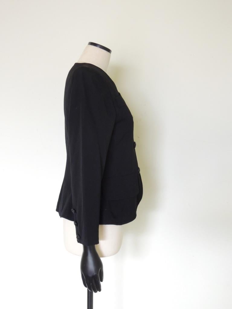 This is a vintage black YSL Rive Gauche collarless jacket, very form-fitting, with decorative buttons, estimating 1980s or 1990s era. Lightly padded shoulders.

The material feels like wool but it is not marked as such.

The jacket size tag has been