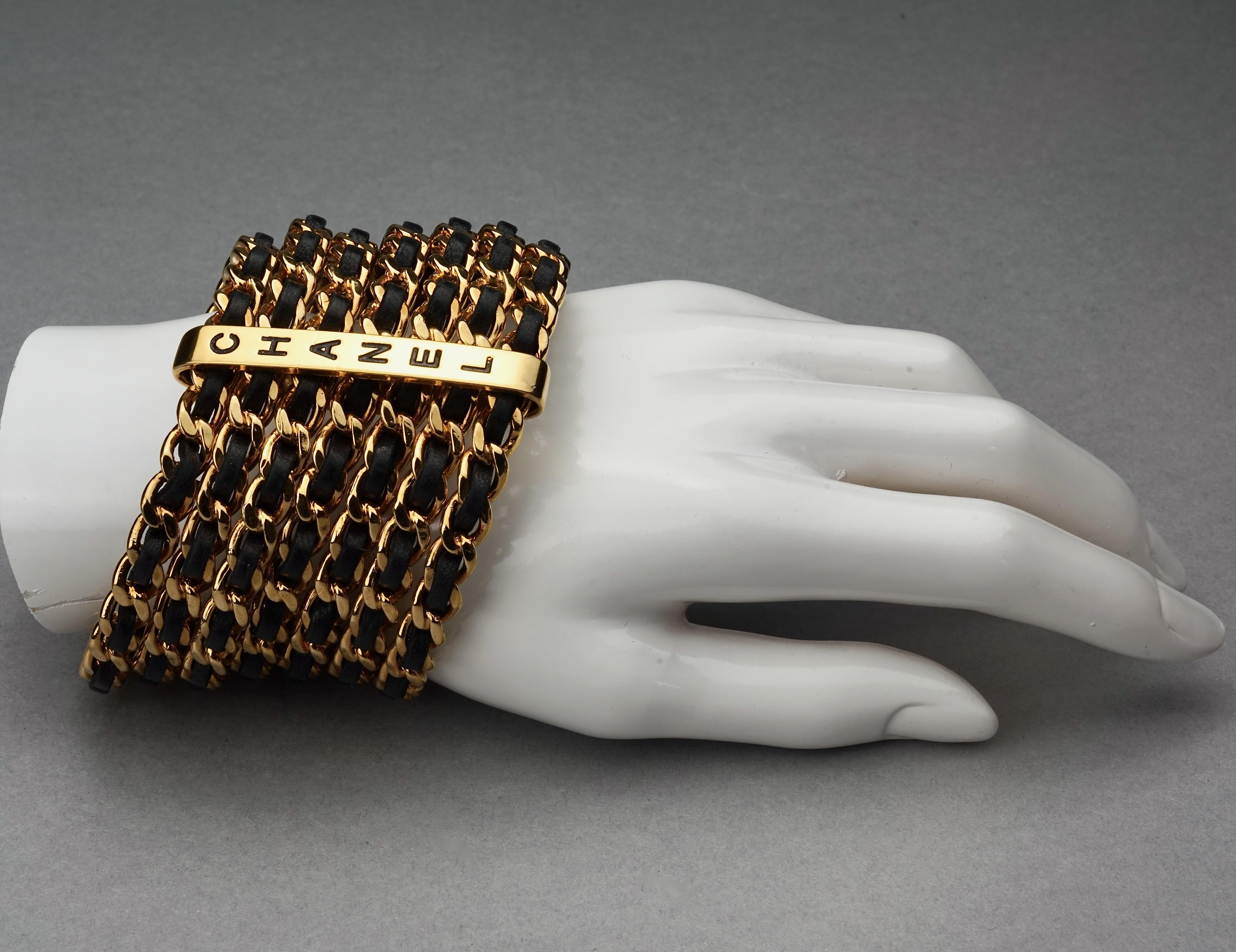 Vintage 1993 CHANEL 7 Stacked Bangles Chain Leather Wide Cuff Bracelet

Measurements:
Height: 2.24 inches (5.7 cm)
Inner Circumference: 7.75 inches (19.7 cm)

Features:
- 100% Authentic CHANEL.
- & stacked bangles in chain and black leather.
- Gold