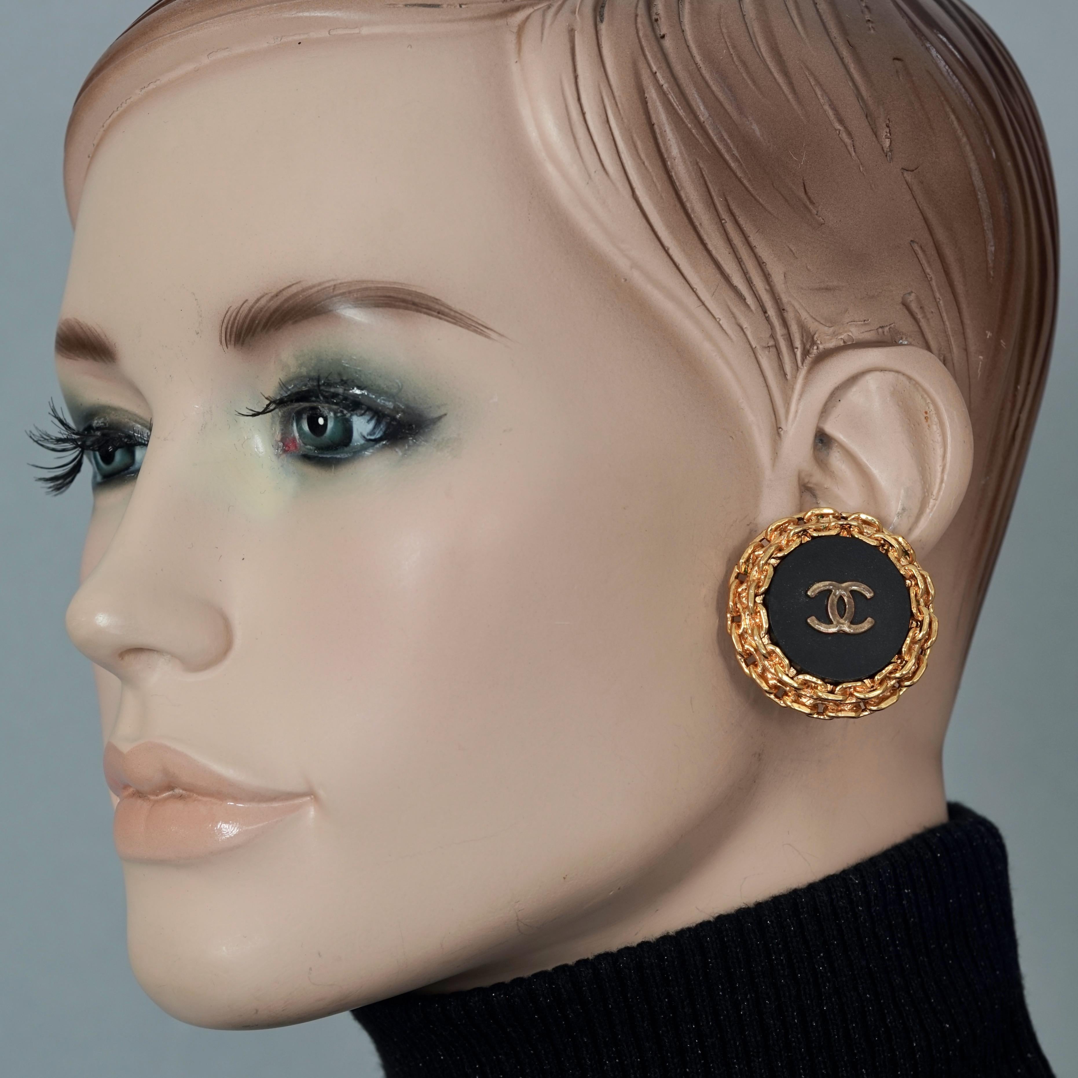 Vintage 1993 CHANEL CC Logo Disc Chain Earrings

Measurements:
Height: 1.38 inches (3.5 cm)
Width: 1.38 inches (3.5 cm)
Weight per Earring: 22 grams

Features:
- 100% Authentic CHANEL.
- Embossed Chanel CC logo on a black resin.
- Rim is with chain