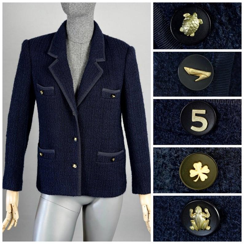 Vintage 1995 CHANEL Navy Blue Tweed Lucky Charm Button Jacket

Measurements taken laid flat, please double bust, waist and hips:
Shoulder: 15.74 inches (40 cm)
Sleeves: 21.45 inches (54.5 cm)
Bust: 18.11 inches (46 cm)
Waist: 18.11 inches (46