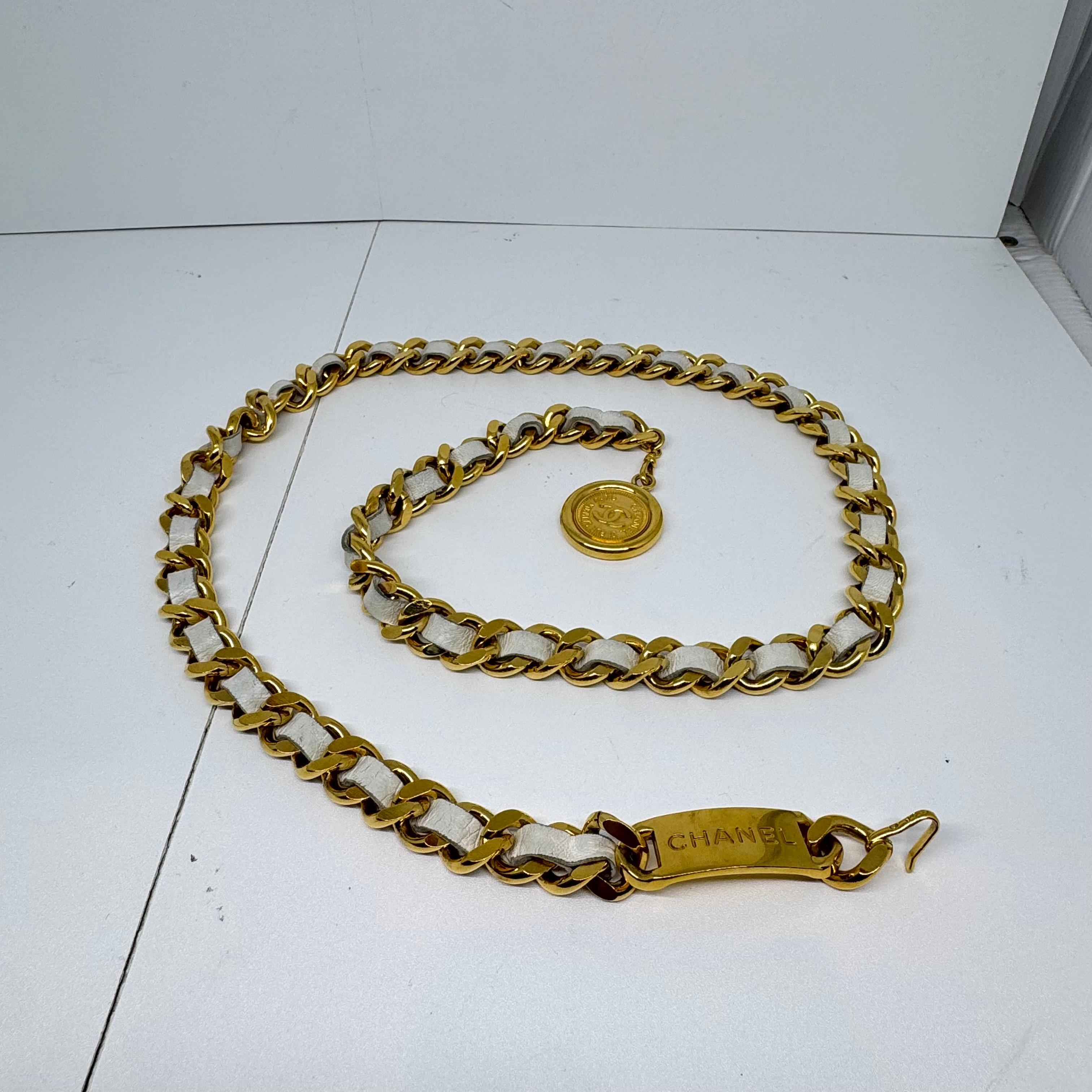 Clásico cinturón de cadena vintage. Apenas viene en blanco. Ligero deslustre en los herrajes y roces en los trozos de cuero. Es posible que se hayan aplicado pequeños retoques en el cuero. Viene con la caja. La longitud es de 95 cm.