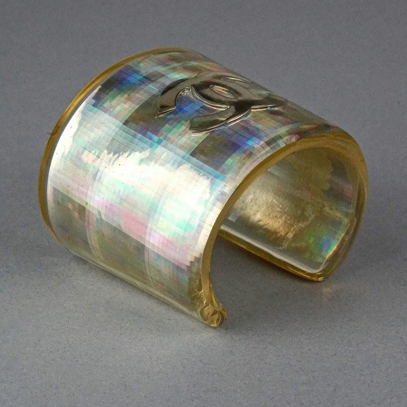 Vintage 1997 CHANEL Logo Holographic Iridescent Lucite Cuff Bracelet

Measurements:
Height: 3.07 inches (7.8 cm)
Circumference: 7.16 inches (18.2 cm)

Features:
- 100% Authentic CHANEL.
- Holographic iridescent acrylic wide cuff.
- CC logo at the