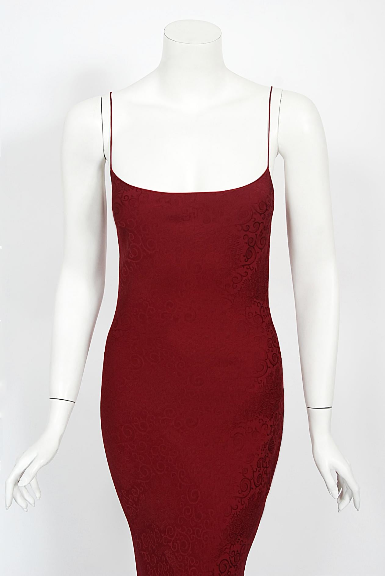 An incredibly chic and highly coveted early John Galliano wine-red peacock patterned stretch silk bias cut slip gown dating back to his spring/summer 1998 collection. These early examples of his work are very collectable and are becoming incredibly