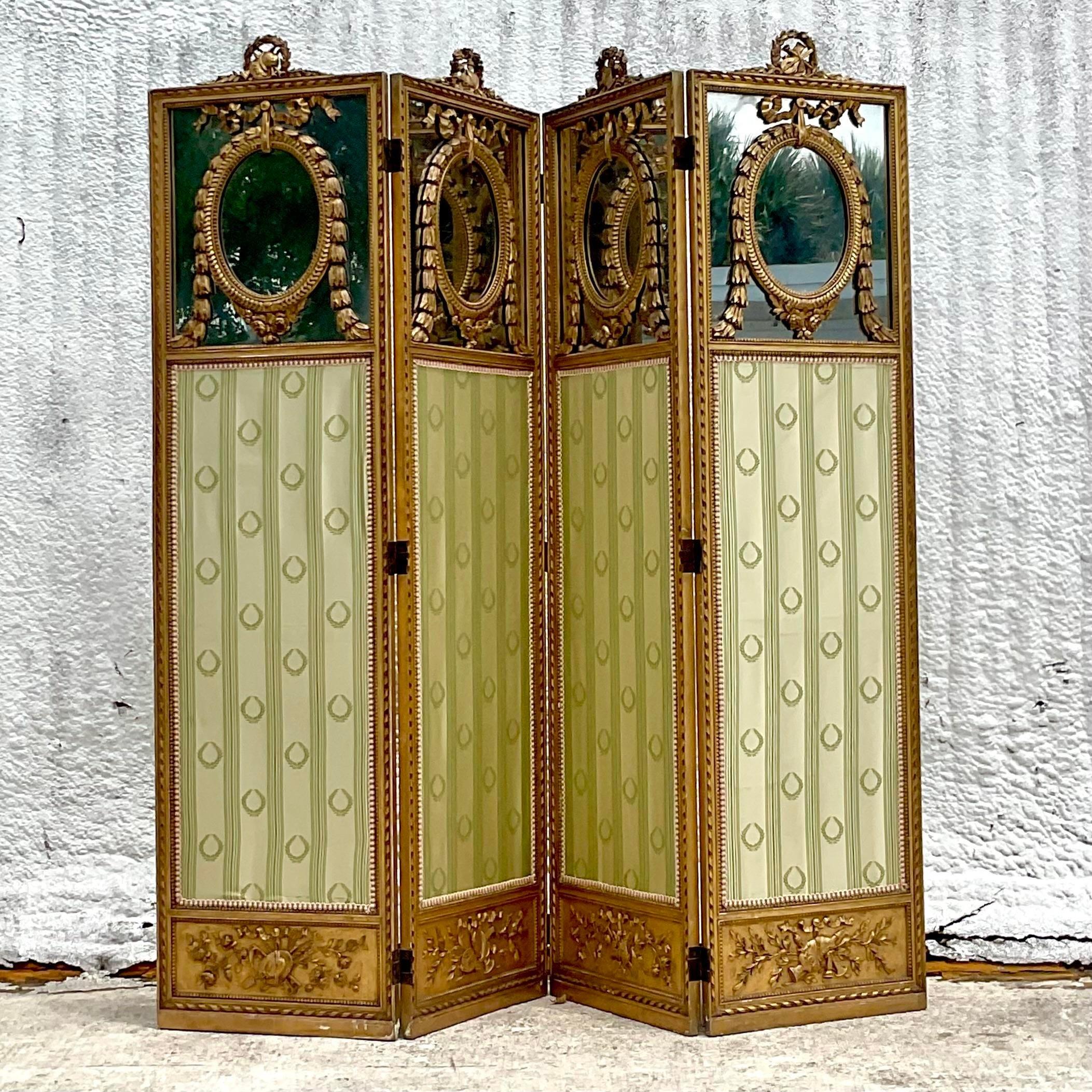 A fabulous 19th Century vintage folding screen. Stunning carved swag detail and inset silk jacquard panels. A wreath of laurels with a mirrored panel at the top. Acquired from a Palm Beach estate.