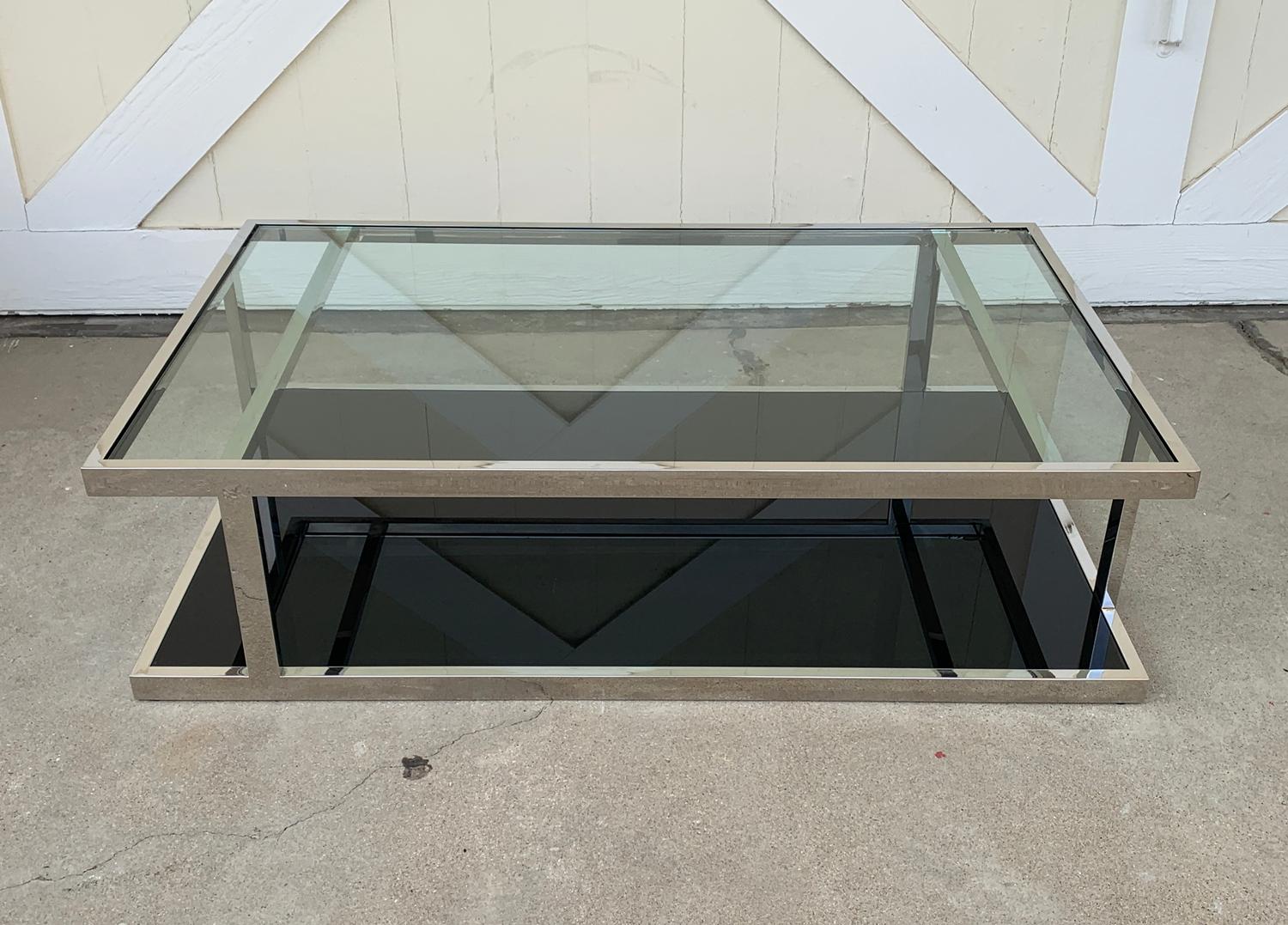 Beautiful two tier coffee table in polished chrome and glass top, bottom glass has reverse painted black glass and the top has a clear glass top.
The table sits low to the ground with only small rubber feet lifting off the ground to avoid