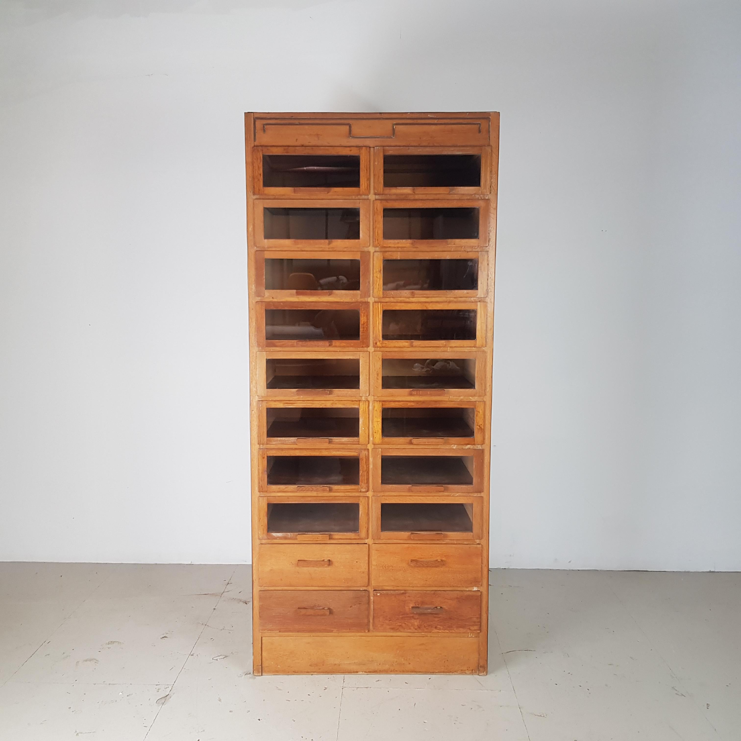 Really lovely vintage 20-drawer haberdashery shop cabinet from the 1940s-1950s with wooden handles. Made by Dudley & Co.
With 16 glass fronted drawers and 4 solid fronted drawers.

In good vintage condition. Some scuffs here and there,