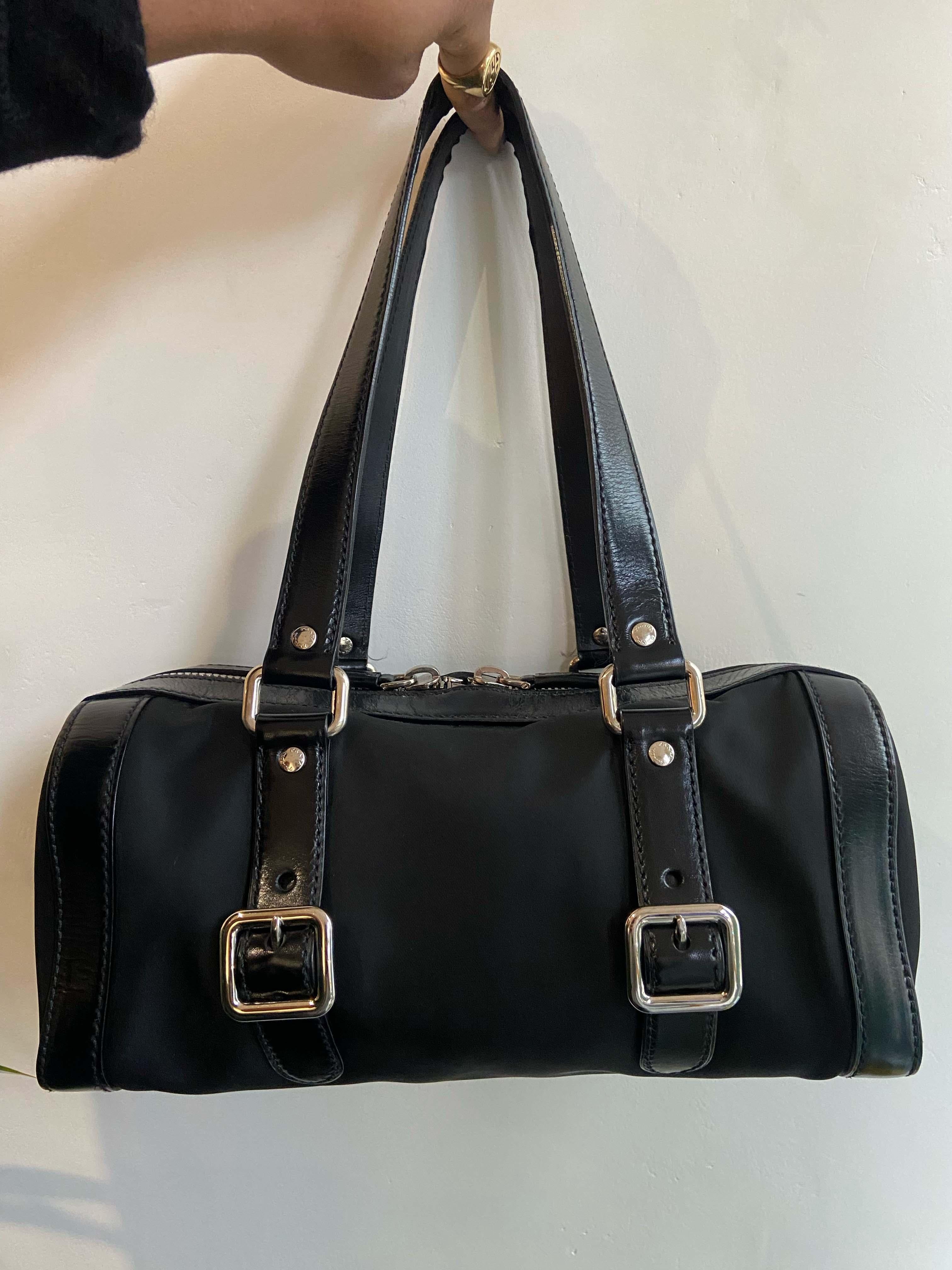 Vintage Prada  1990’s bowling bag. Features black nylon fabric  two back interior zip pockets. Leather strap,   and Prada front logo. Double zip closure.

Brand: Prada
Color: Black
Fabric: Nylon, Leather
Year / Season: Circa 2000's
Authenticity