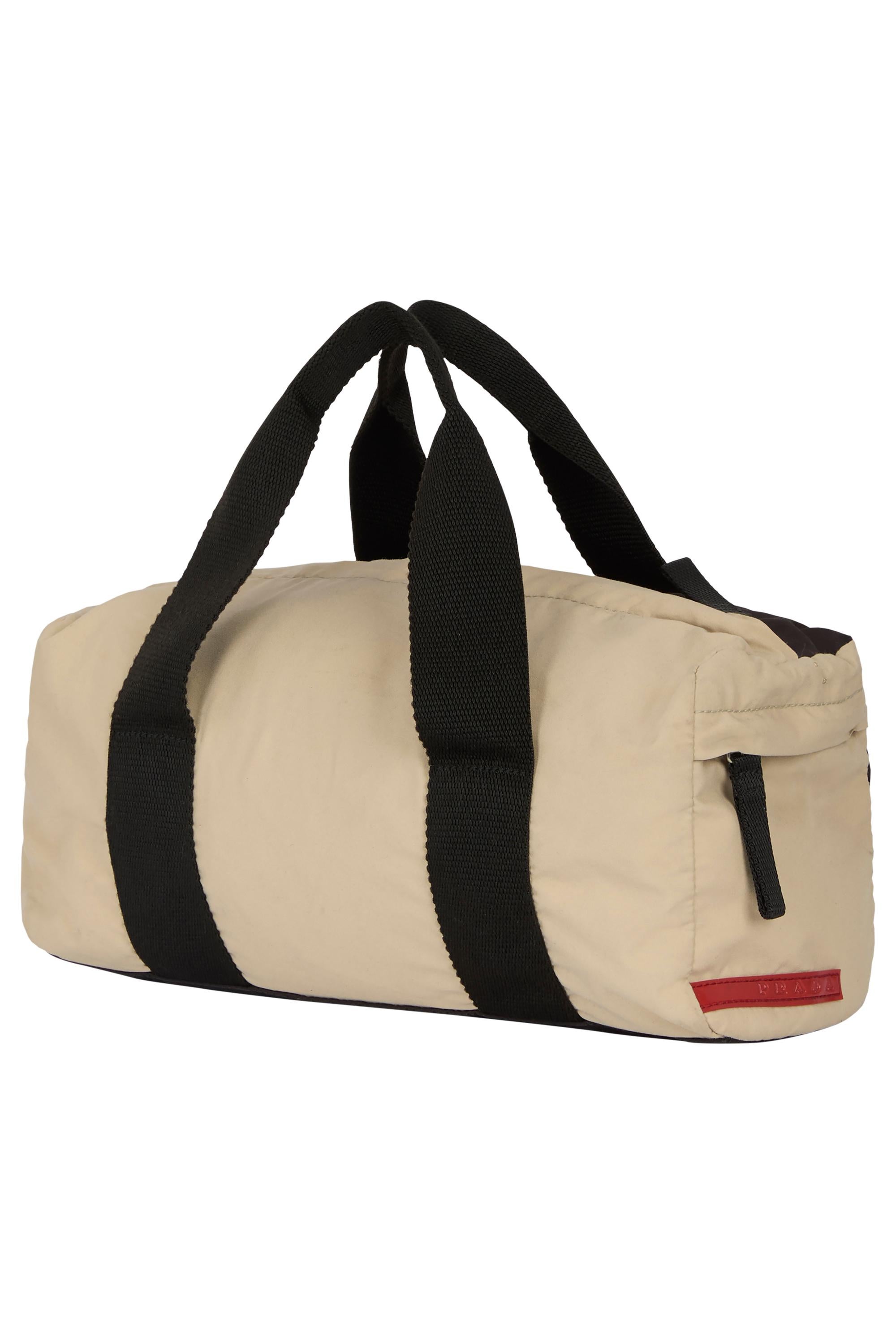 Vintage 2000's Prada two tones mini duffle tote . Features a two-tone beige and black  nylon fabric, wide black webbing straps, small side zip pocket, red Prada logo tab and a striking red contrast seam across the back panel. Main compartment,