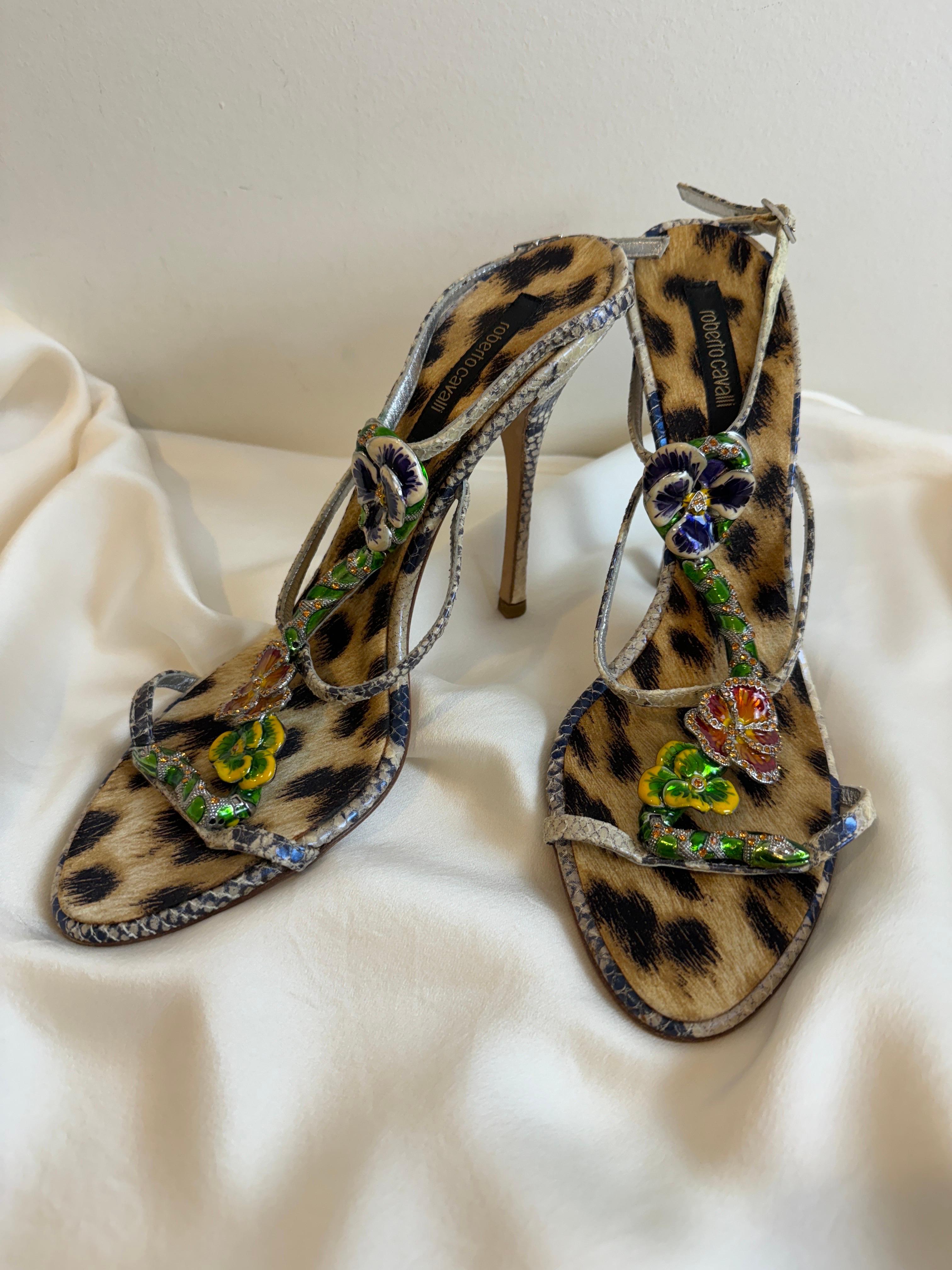 Vintage 2000s Roberto Cavalli heels
Ankle wrap style with silver buckle closure
Ornate enamel + rhinestone snake + flower details on the front supported by 3 straps across the shoe
Leopard foot bed
Grey + off white iridescent snake pattern leather