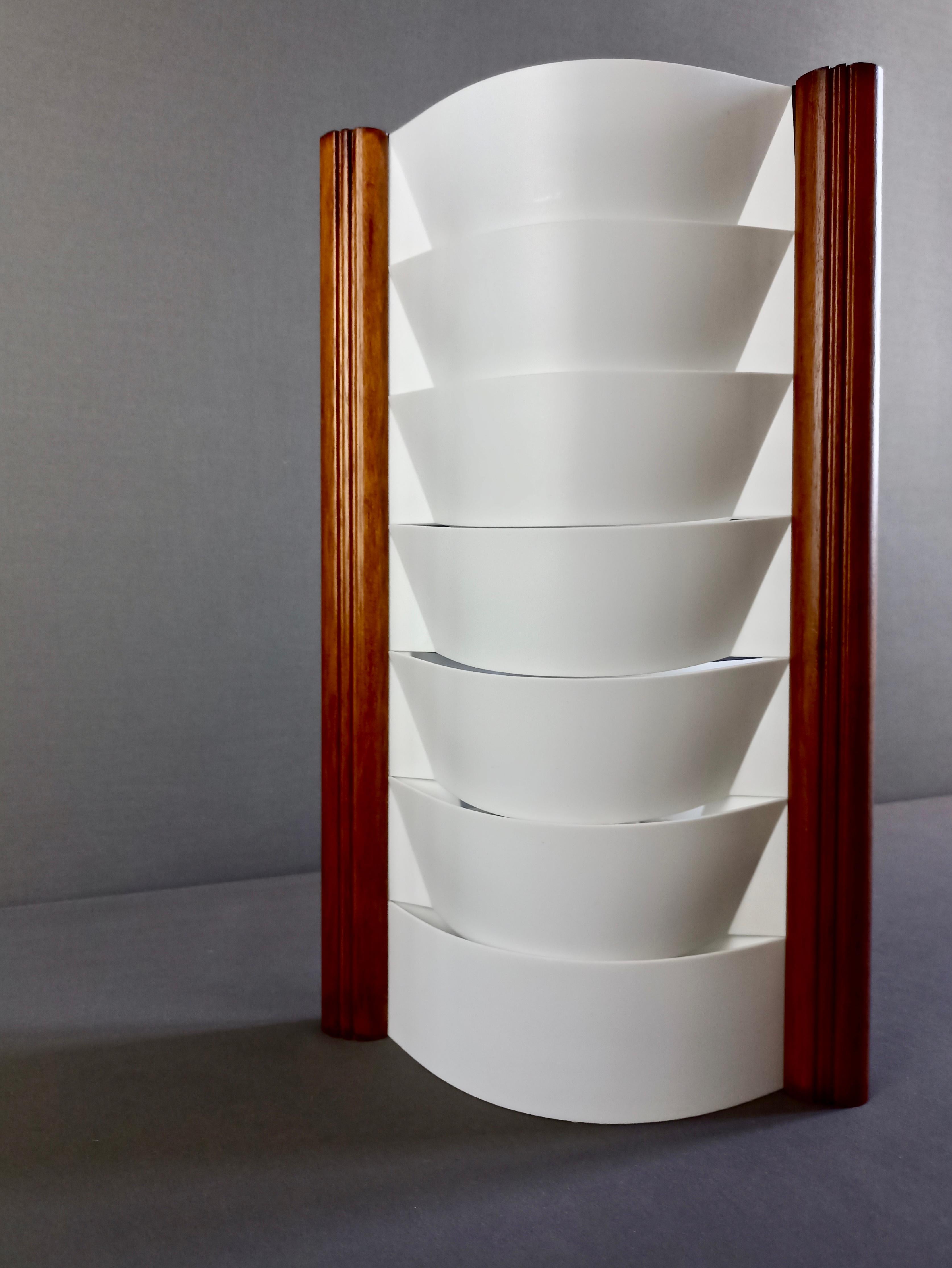 Schöne minimalistische Slamp S-Tube Samuel Parker Tischleuchte aus den frühen 2000er Jahren, aus weißem Opalflex-Kunststoff und walnussfarbenem Holzrahmen.
Perfekt, um ein sanftes Umgebungslicht zu schaffen, ist sie aufgrund ihres Designs auch ein
