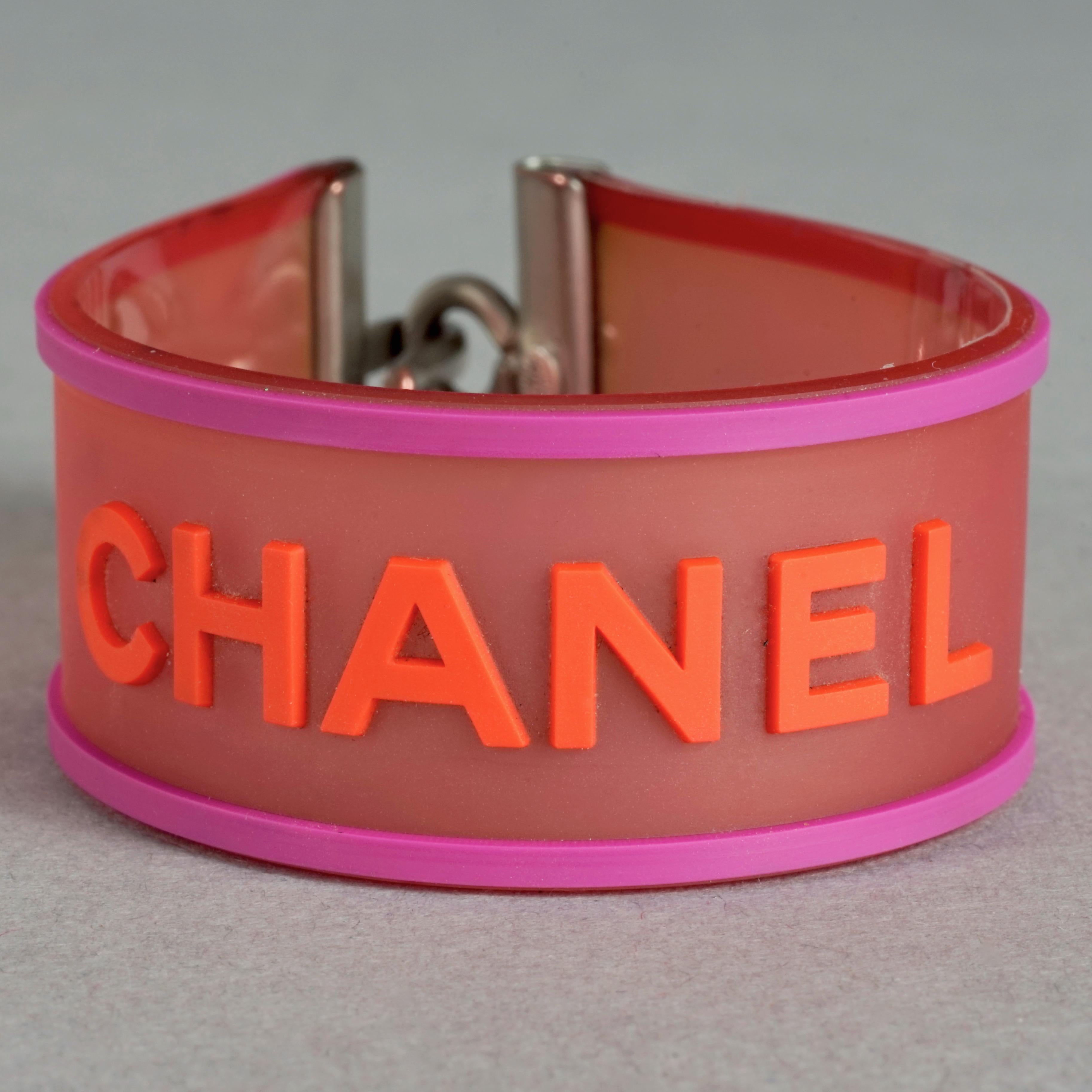 Vintage 2001 CHANEL Logo Camellia Pink Orange Rubber Cuff Bracelet

Measurements:
Height: 0.90 inch (2.3 cm)
Circumference: 6.50 inches (16.5 cm)

Features:
- 100% Authentic CHANEL.
- Translucent pink rubber with embossed CHANEL and camellia