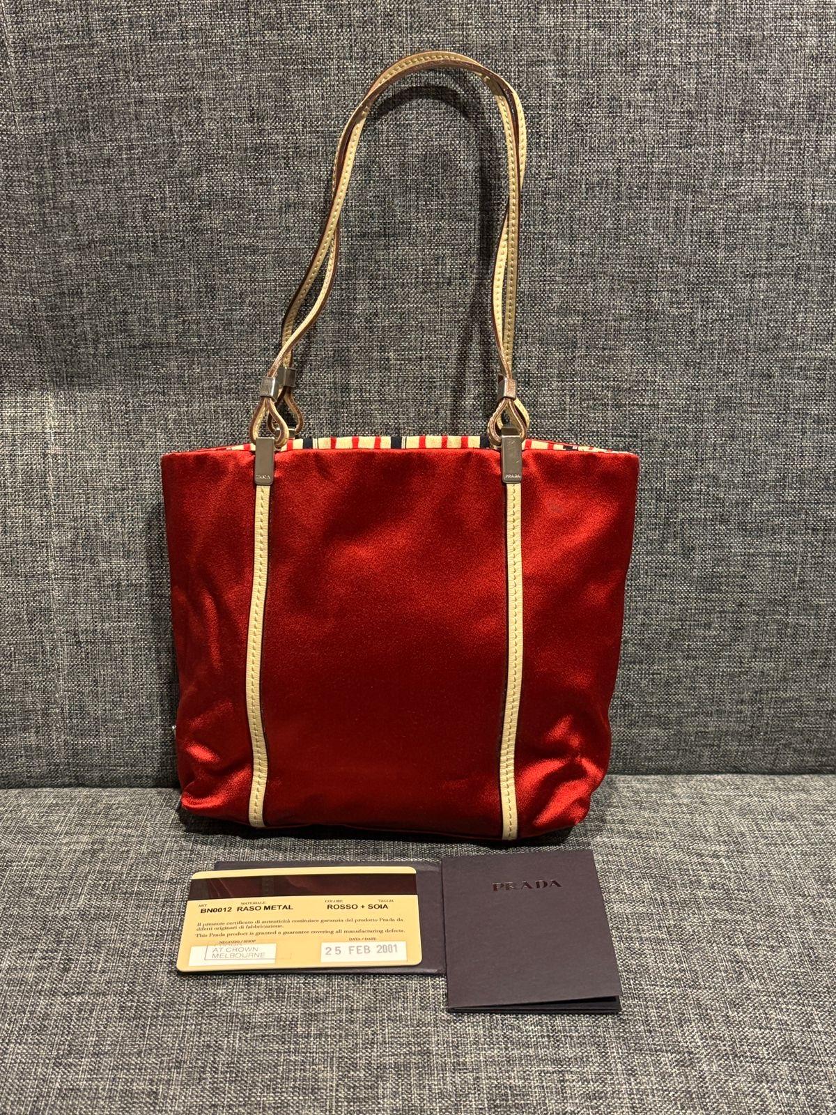 Vintage Prada mini satin bag in red. Very cute vintage style. White leather list with stripe lining. Red triangle logo on the side. Comes with its card. Minor marks on the bottom of the bag.