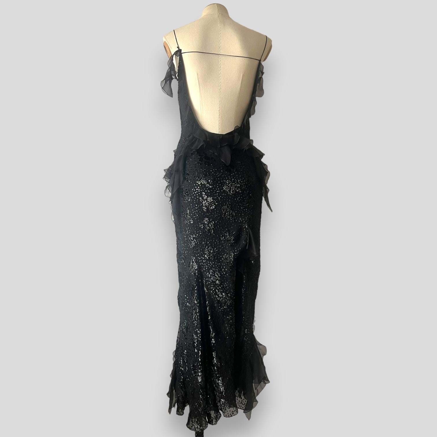 The vintage John Galliano creation for Christian Dior showcases his signature flair for dramatic elegance, crafted in 2004. This black silk gown is adorned with intricate metallic floral embroidery, complemented by a cowl neckline, a daring side