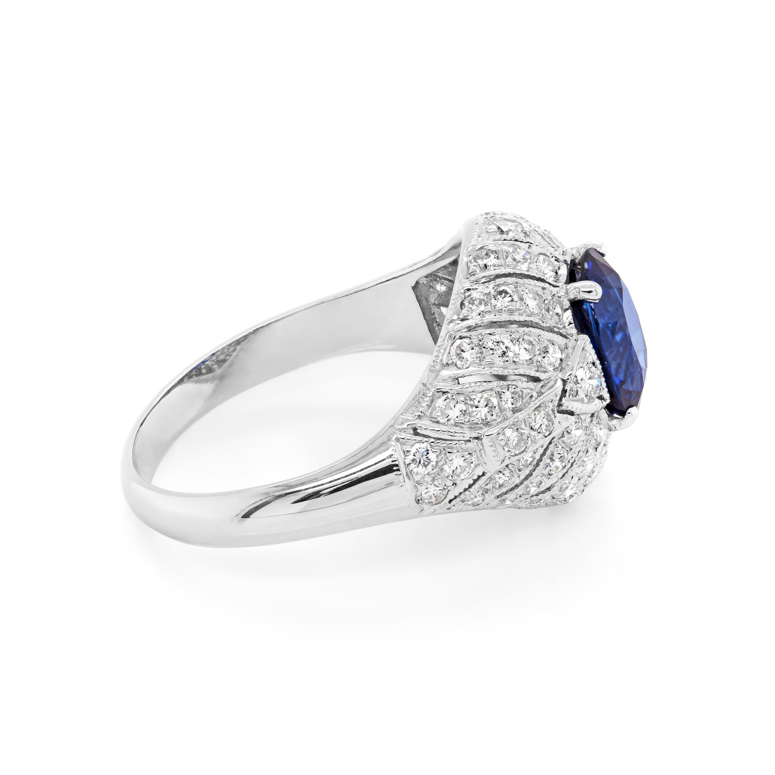 Beautiful 1950's engagement ring set with a royal blue natural sapphire in a 4 claw setting. The stone is mounted in the centre of an intricate Deco style bombé cluster, grain set with 72 round brilliant cut diamonds with an approximate total weight