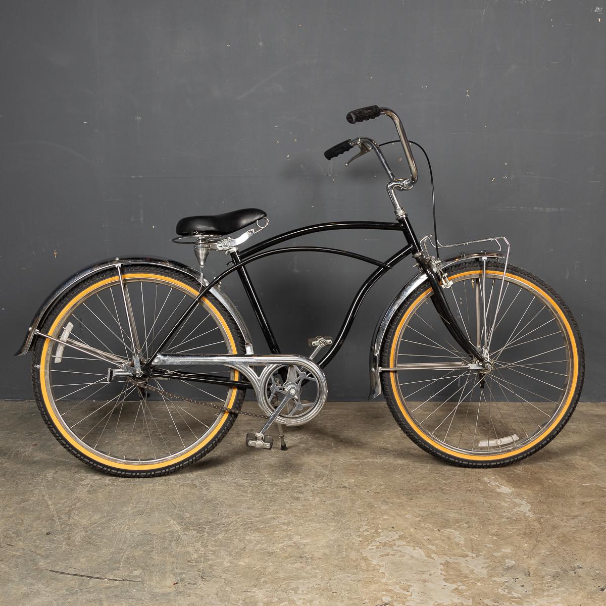An impeccably restored Dutch fixed gear bicycle from 20th-century Amsterdam. Crafted in the 1950s, it boasts polished metal mudguards, a chain guard, and vintage-style handlebars. Its padded seat, equipped with spring-loaded suspension, ensures a