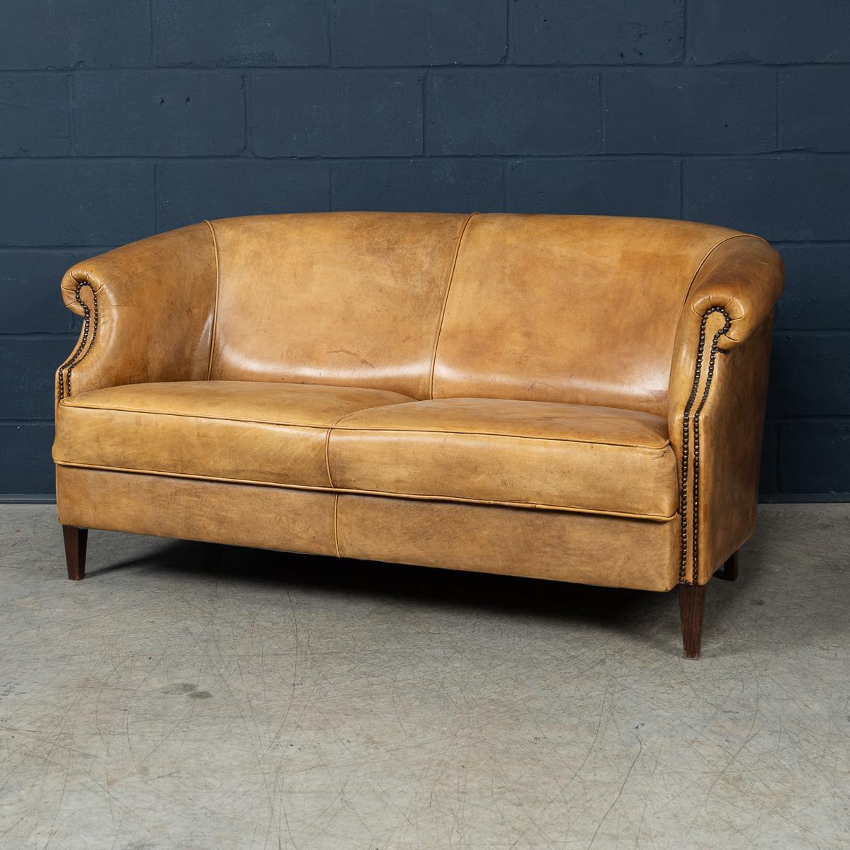 Exhibiting a superb patina and rich, mellow tones, this exceptional sofa was hand-upholstered in sheepskin leather by master craftsmen in Holland during the latter part of the 20th century. The depth of character in the leather, combined with the
