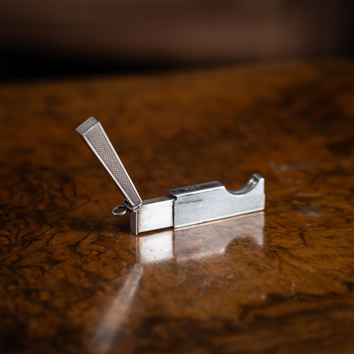 Superbe coupe-cigare compact en argent massif Dunhill du 20e siècle, de forme rectangulaire avec un anneau de suspension pliant sur un côté. Lorsqu'il est ouvert, le coupe-cigare s'allonge d'environ 1,5 cm, ce qui permet de couper proprement les