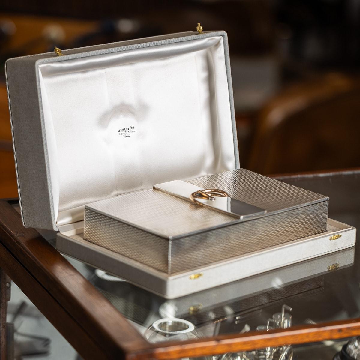 A superb vintage 20th Century solid silver cigar box by Hermès. The box showcases an engine-turned diagonal pattern on the exterior, adorned with a gilt central belt buckle design on the lid. Inside, it is richly gilt and includes two compartment