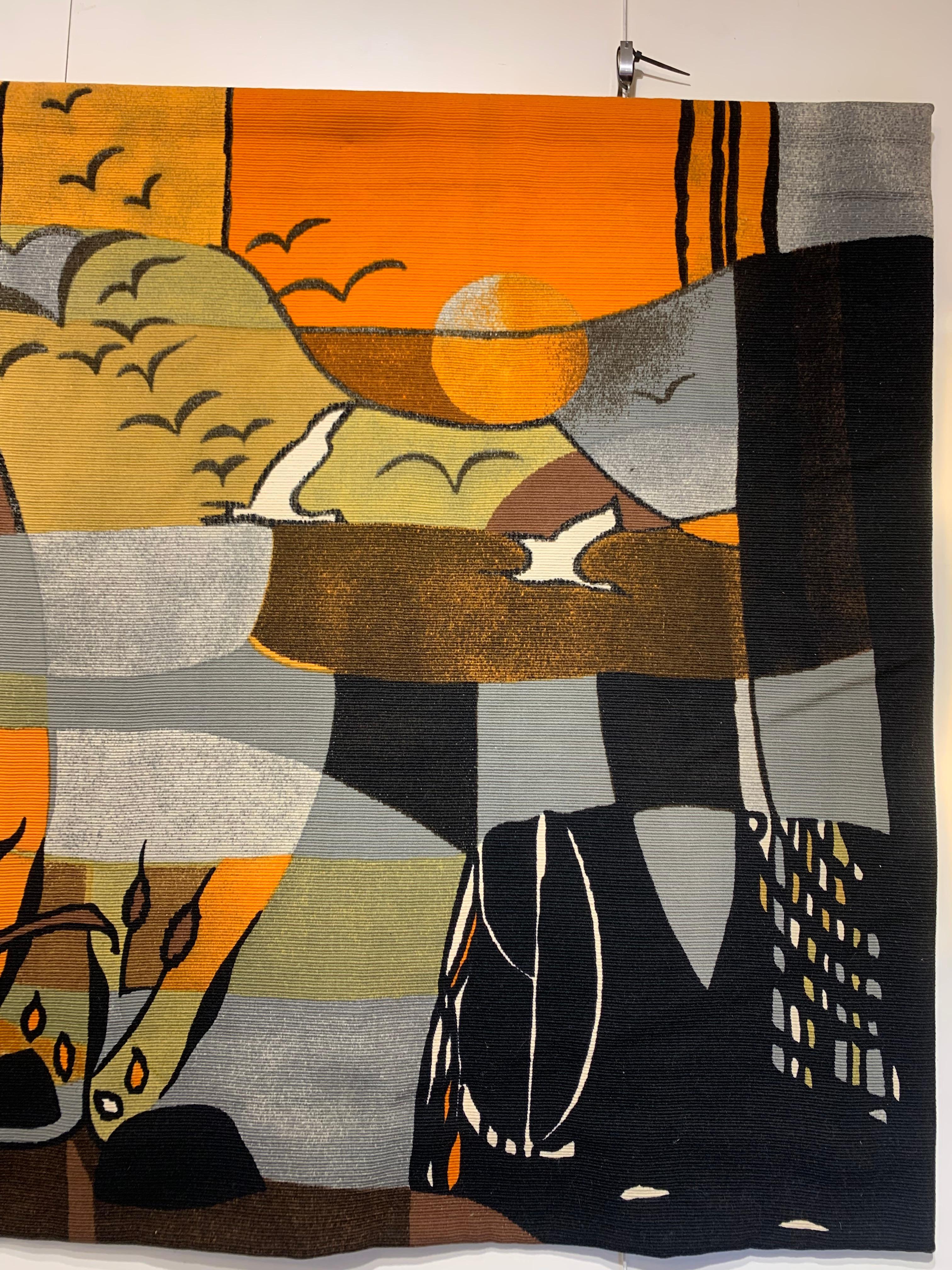 Decorative wall tapestry straight from the 1970s signed by Michele Cahard hand-woven in wool. It depicts a nature scene of birds flying towards the sunset and over a swamp with plants and some trees, using geometric forms and catchy earthy colours,