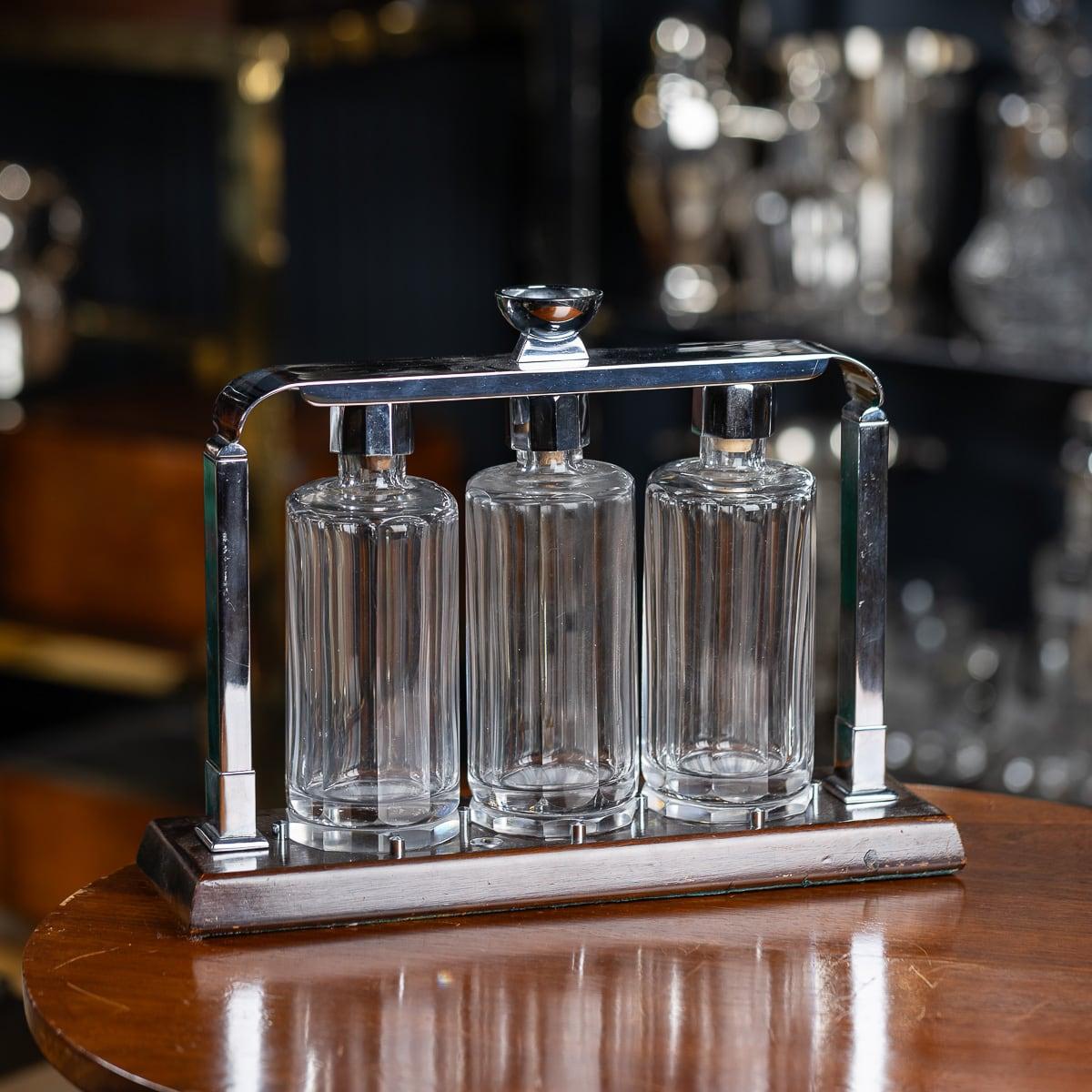 A 20th Century Art Deco Italian made wood and chrome Tantalus, featuring a wooden base with a chrome locking mechanism. Three cut-glass decanters with stoppers are securely housed in the lockable frame. A sophisticated way to entertain guests, this