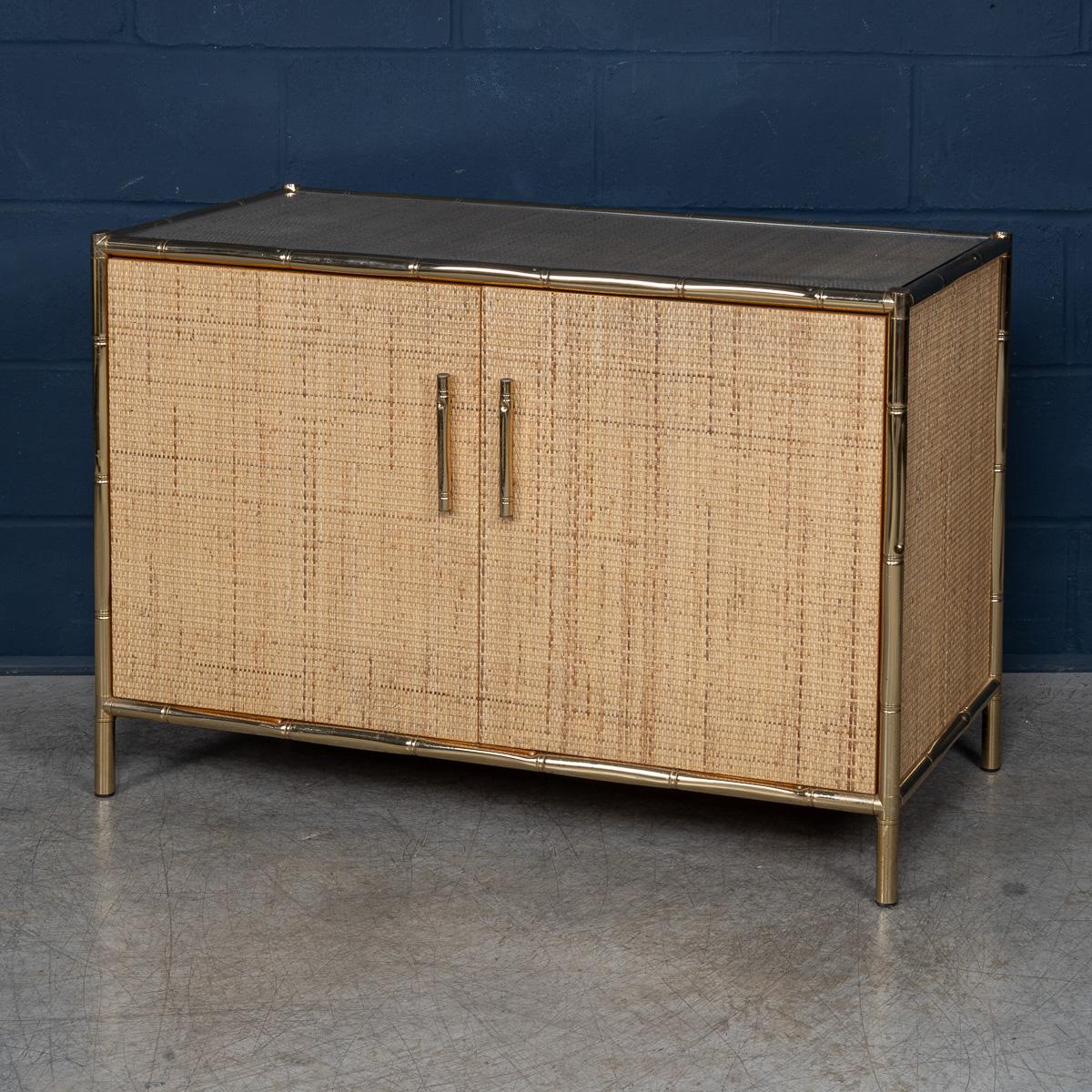 Questo accattivante mobile, realizzato in Italia intorno al 1980, unisce il calore del rattan e del bambù finto all'eleganza di una struttura in ottone lucido. Costruita secondo standard rigorosi, la sua struttura leggera ma robusta è caratterizzata