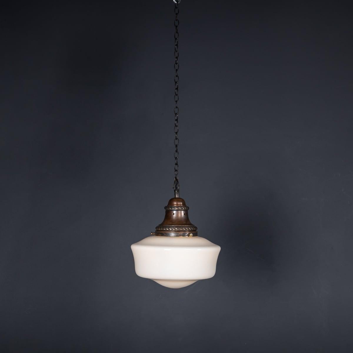 A mid 20th Century English pendant light, made from white opaque glass with the original copper tops. A simple art deco style light which was once used in grocery stores above the counters in the glamorous 1930's. Perfect for enhancing